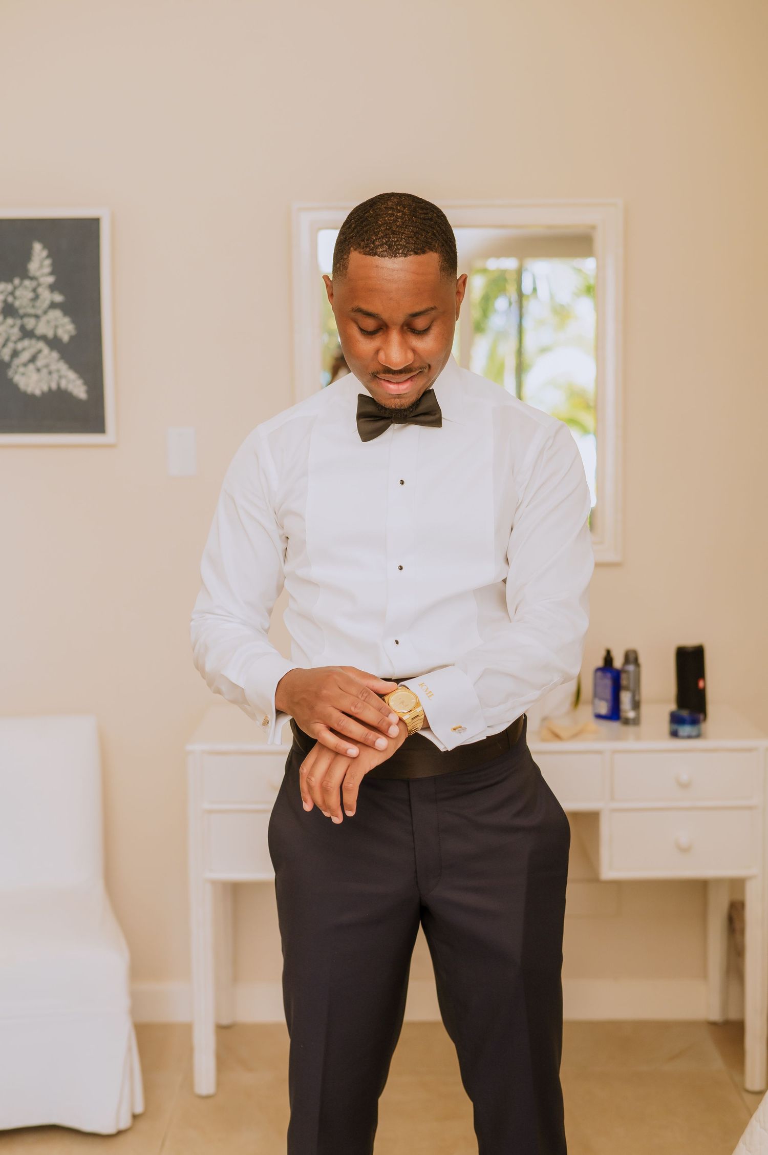 Groom adjusts cufflinks while getting dressed in formal attire.