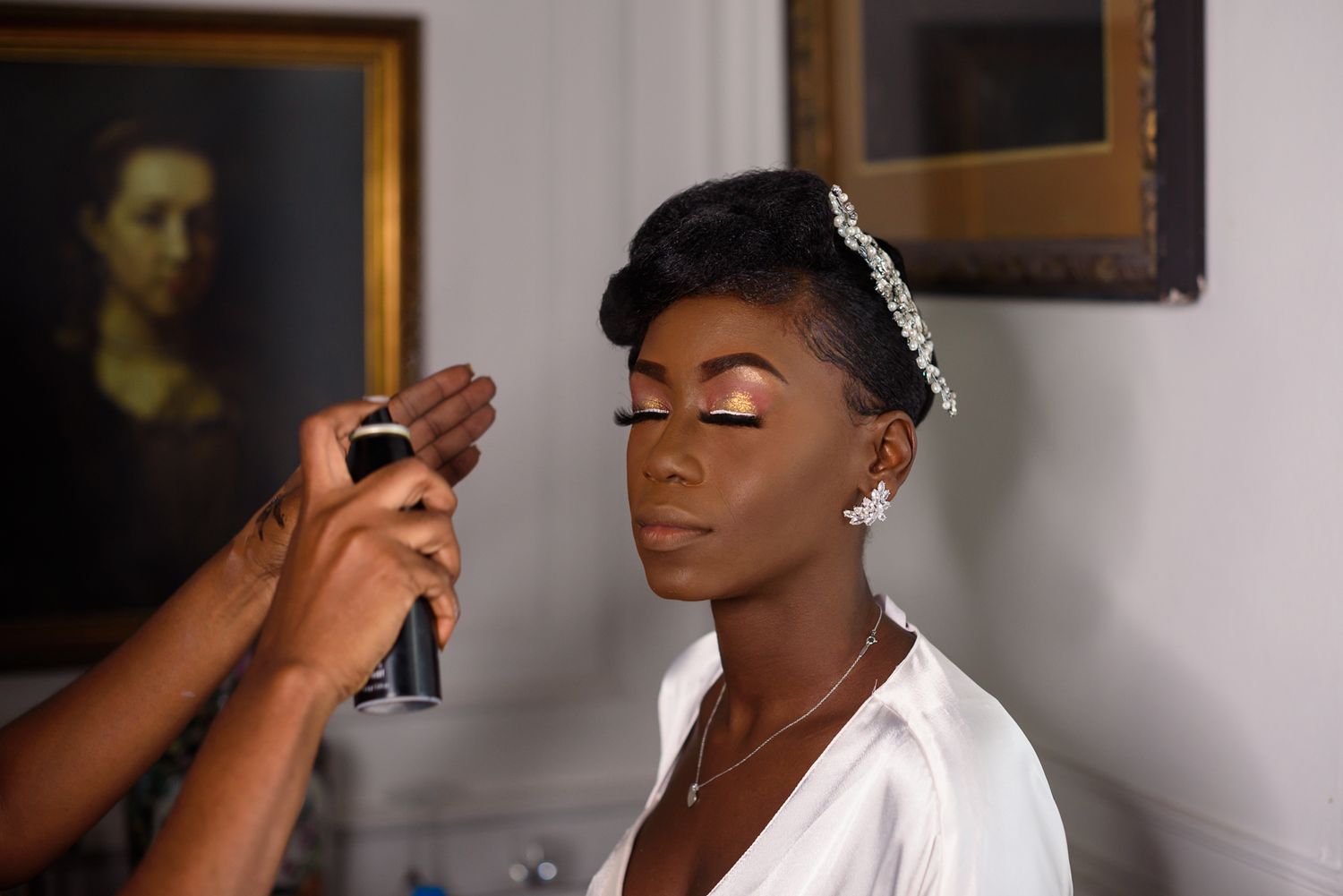 A makeup artist applies cosmetics during bridal preparation in an elegant room.