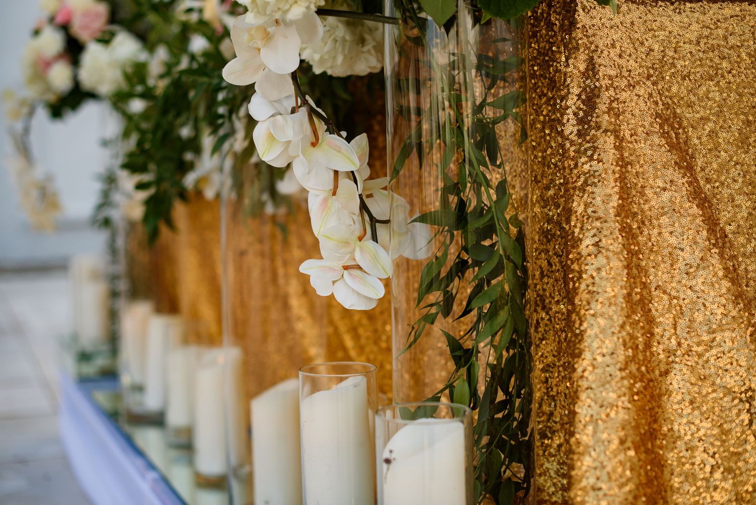 Elegant wedding reception table settings with gold sequin tablecloths and white floral centerpieces.