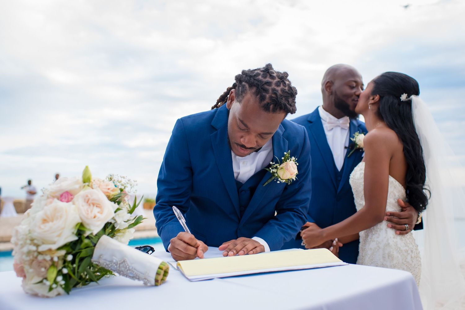 Wedding ceremony participants signing documents at an elegant beach venue.