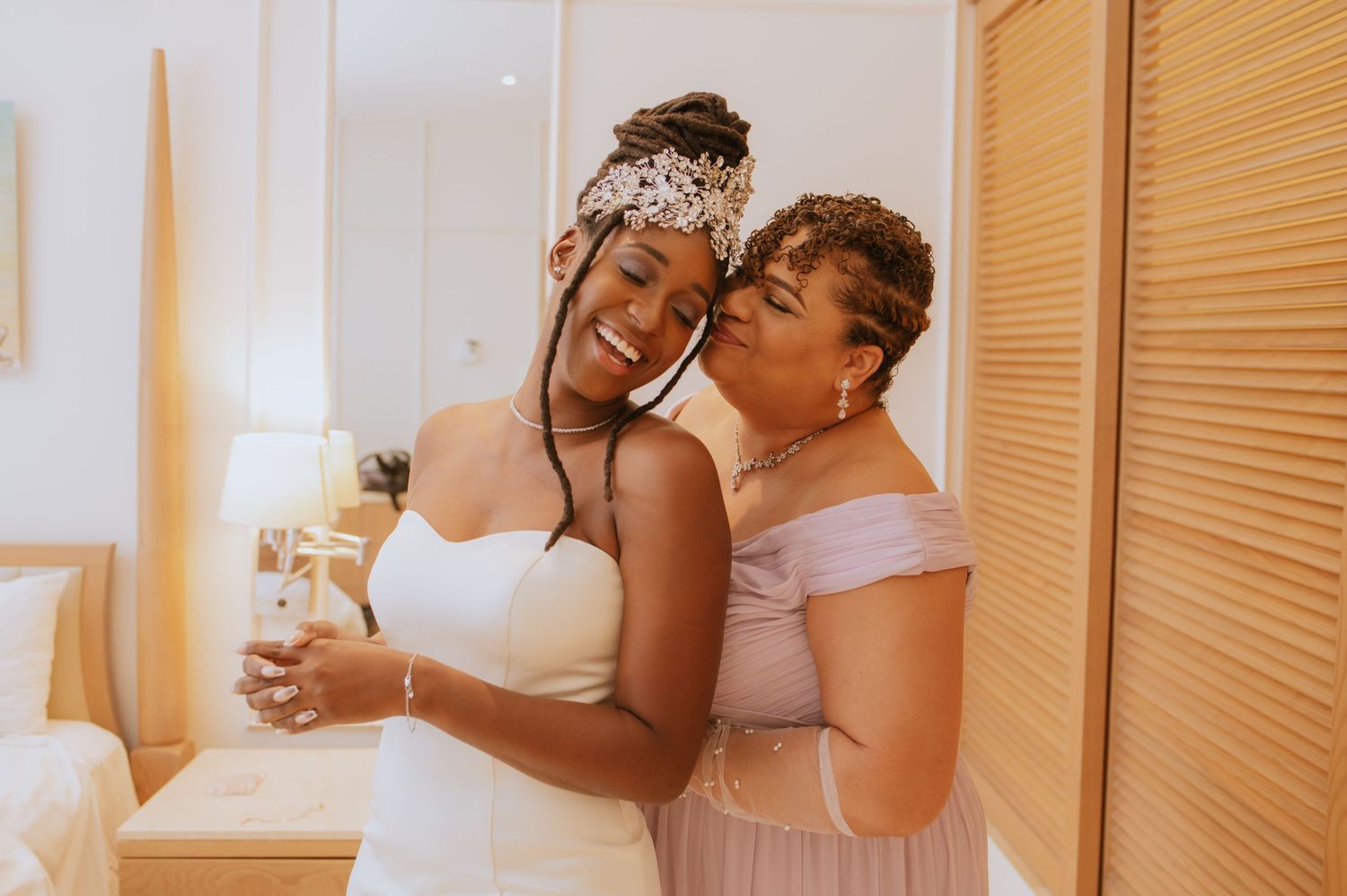 Joyful moment between bride and bridesmaid sharing champagne during wedding preparations.