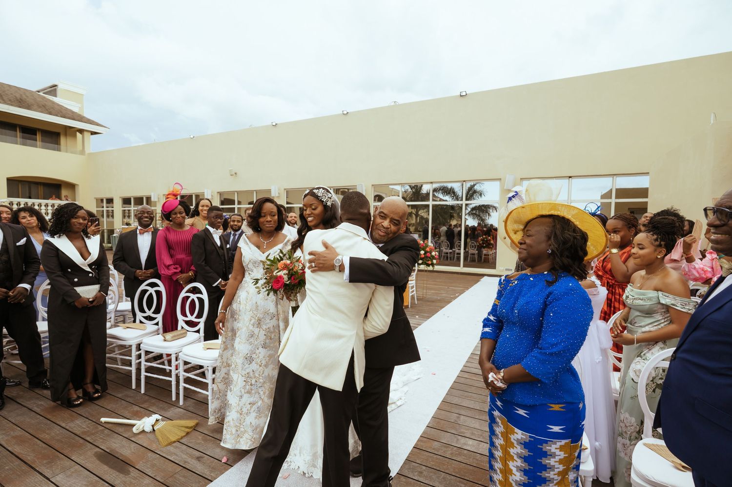 Joyful wedding celebration on outdoor deck with guests in formal attire.