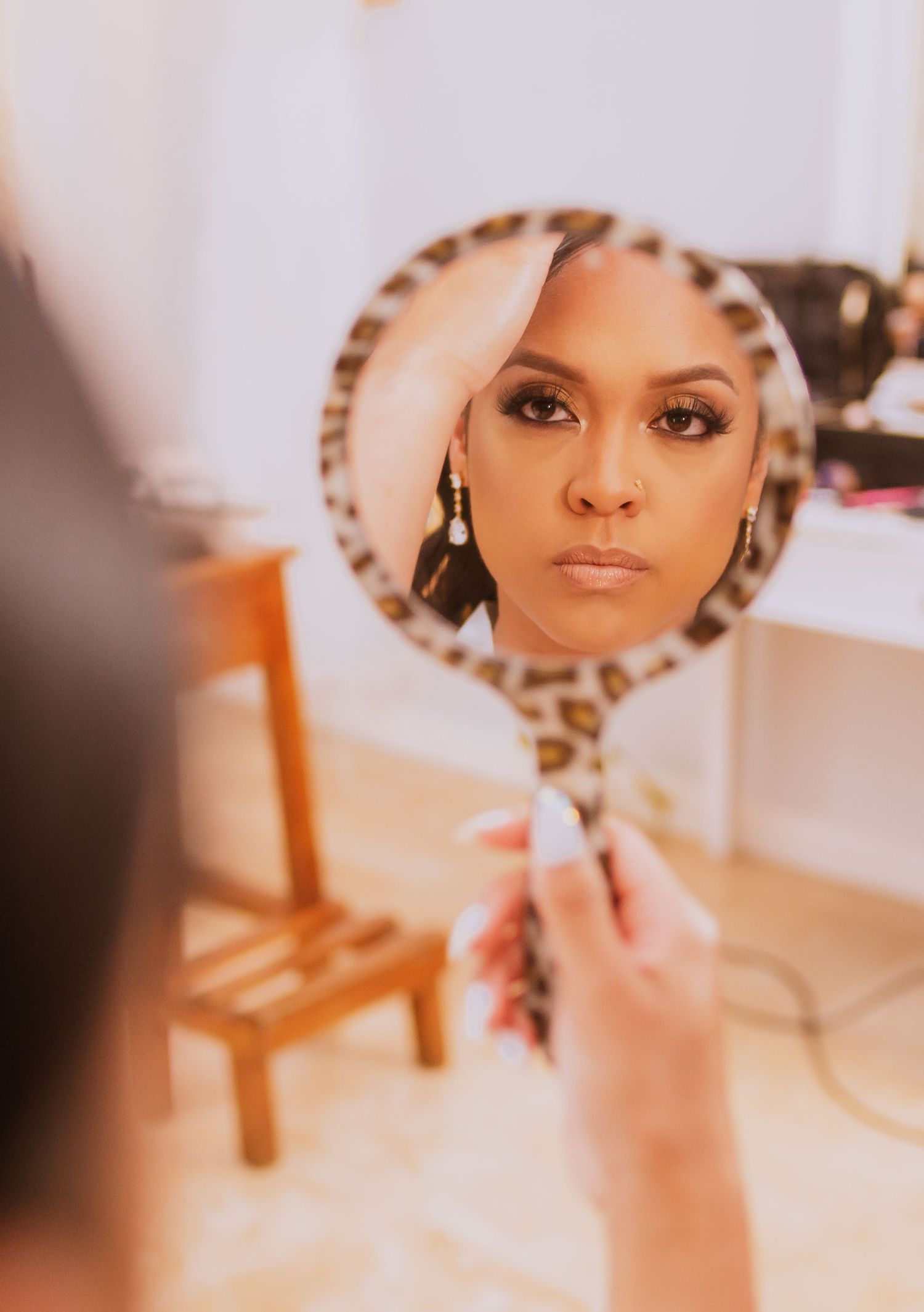 Wedding makeup preparation scene reflected in an ornate mirror.