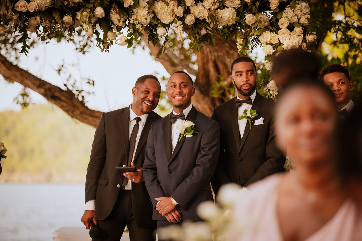 Wedding guests and party members gather under warm lighting at outdoor reception.