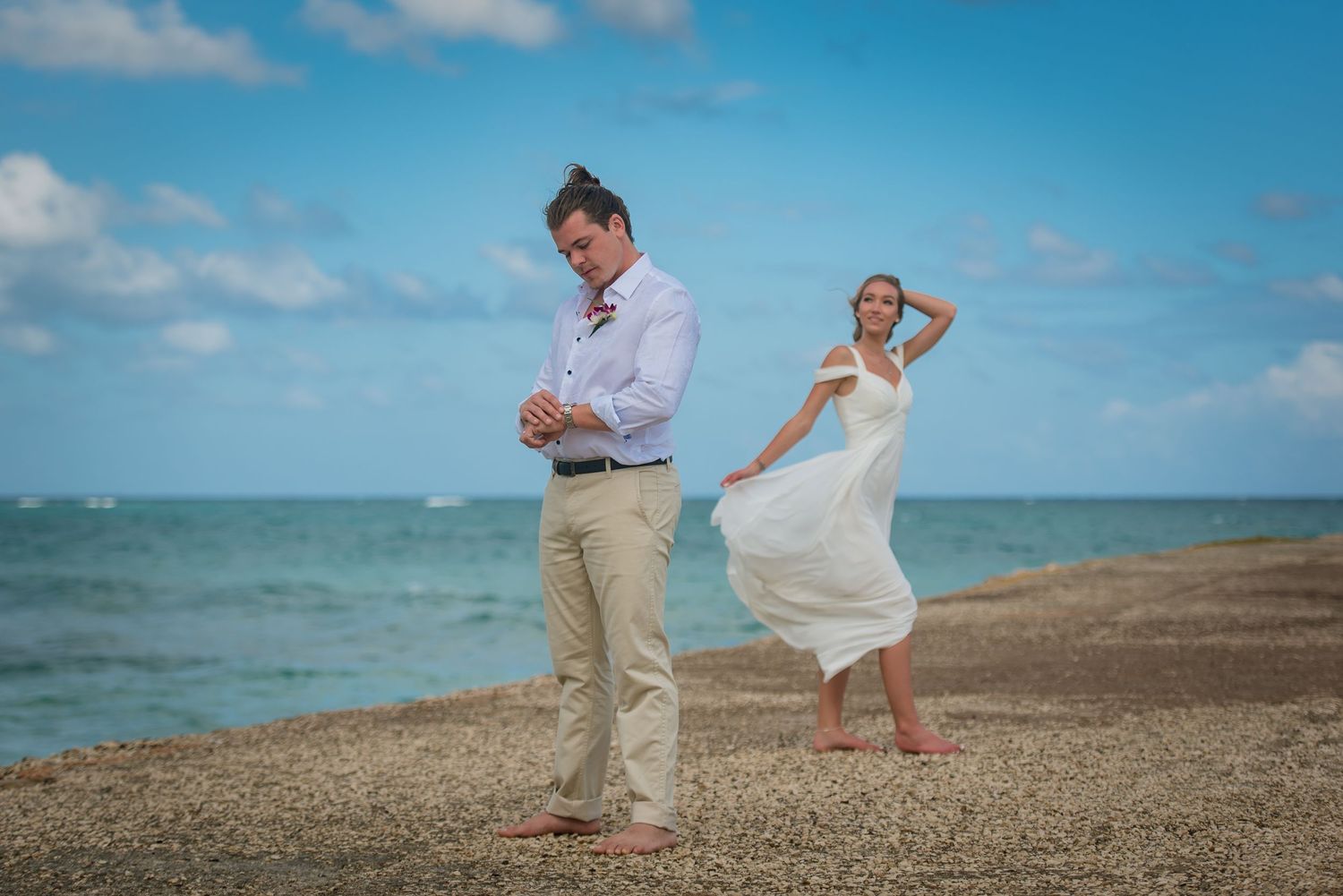 Beachside wedding photography session with turquoise ocean and blue sky backdrop.