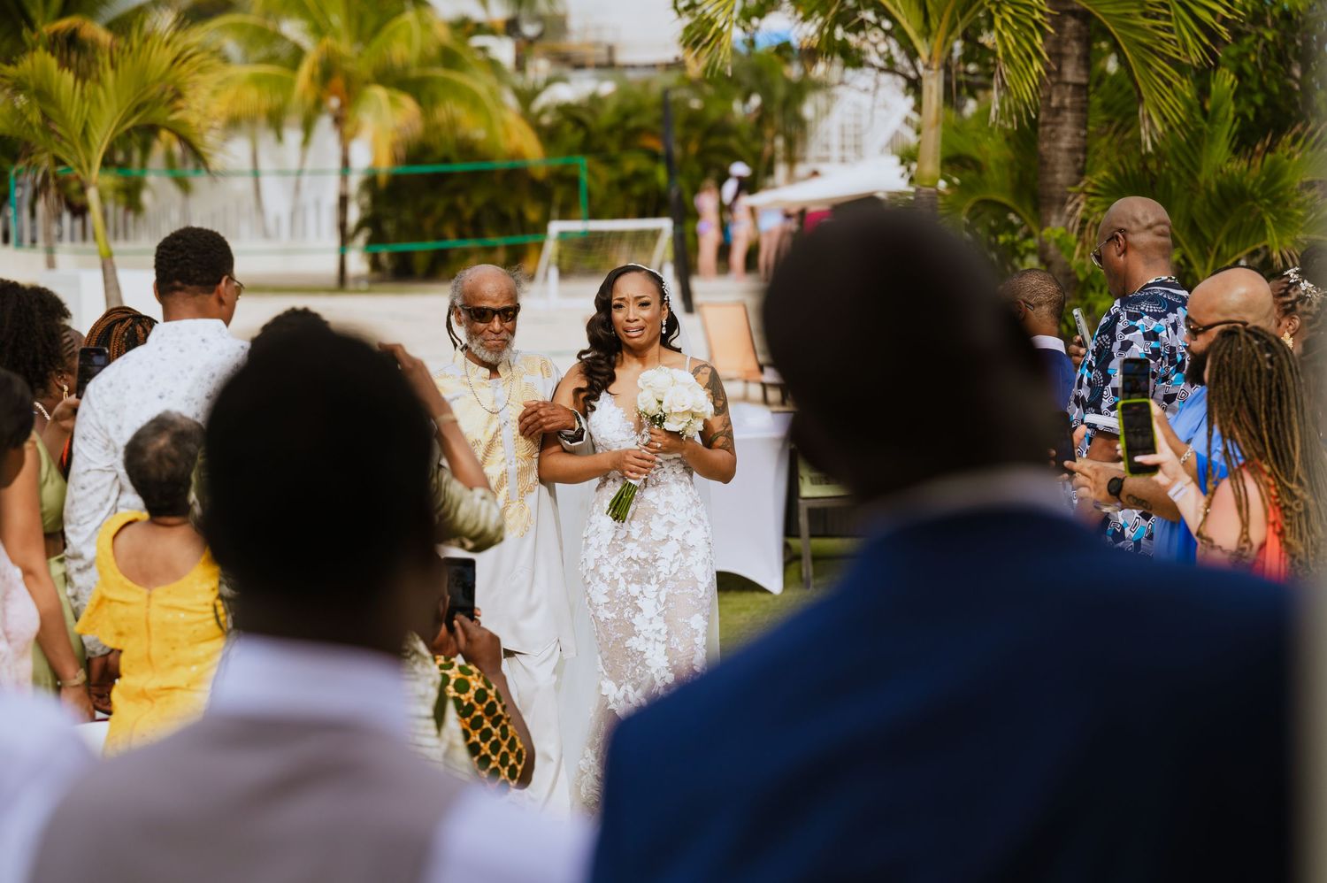 Wedding guests celebrate during outdoor tropical beach ceremony.