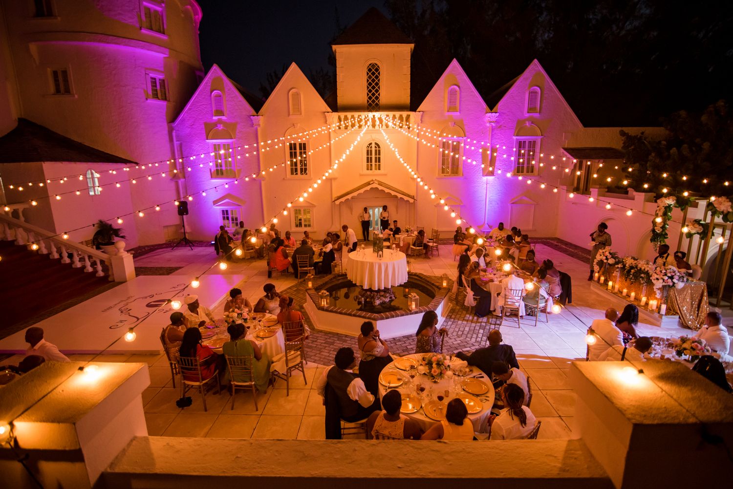 Nighttime wedding reception with pink uplighting illuminating architectural details.