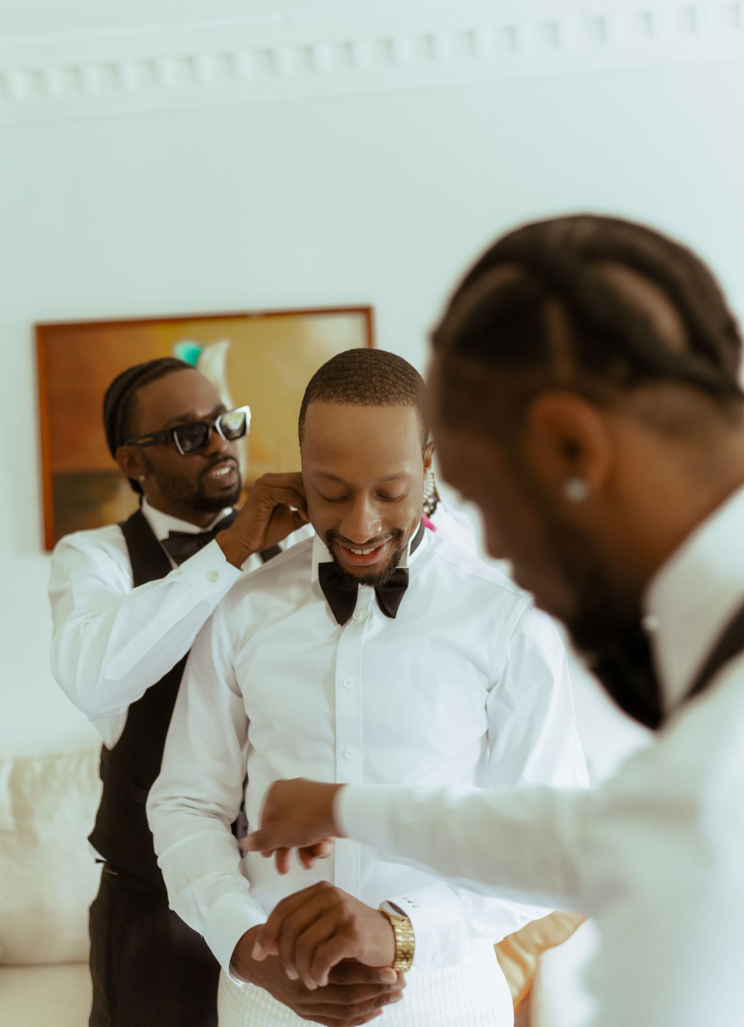 Wedding party in white formal attire getting ready in a bright indoor space.