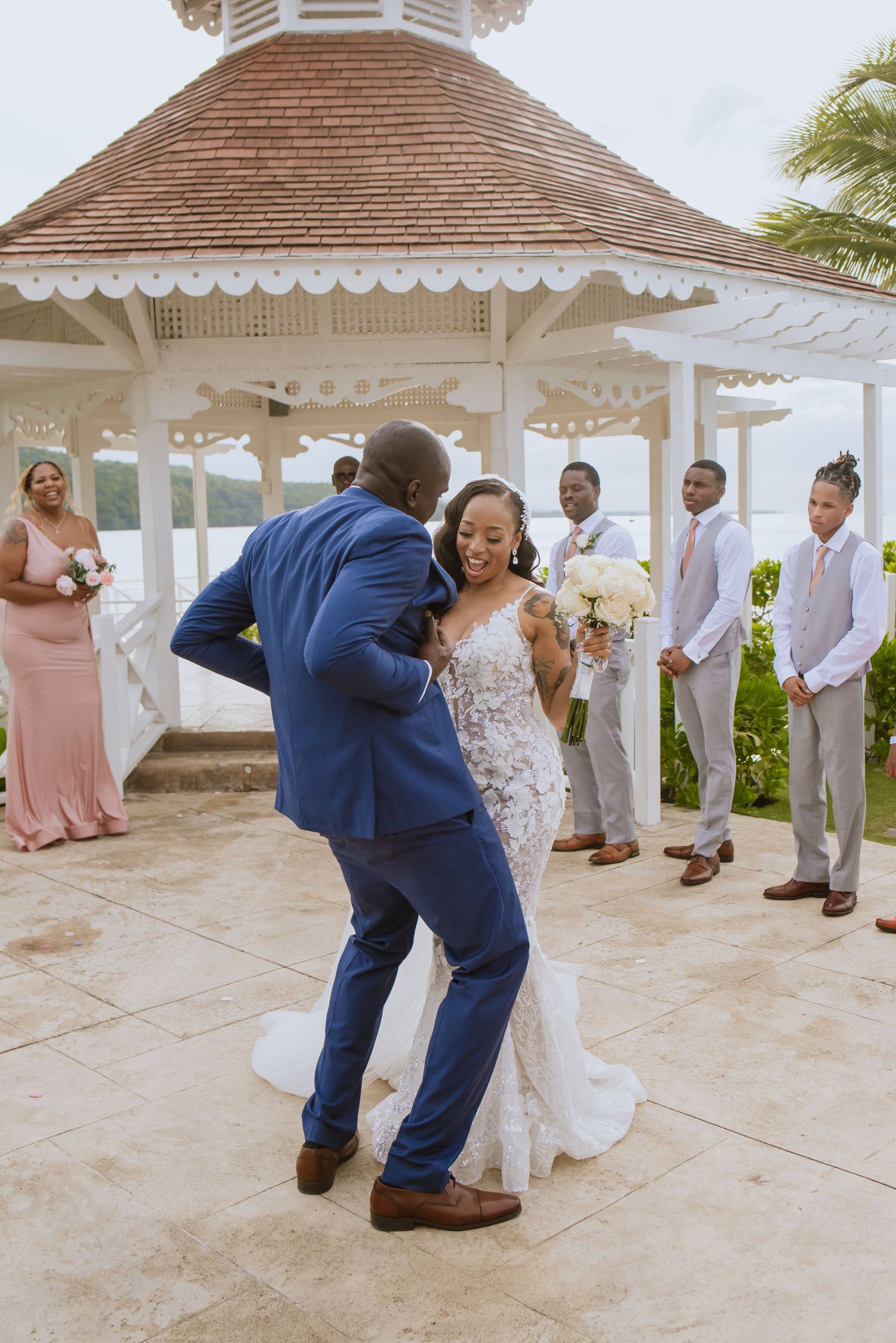 A couple dances together during their wedding celebration under an ornate gazebo.