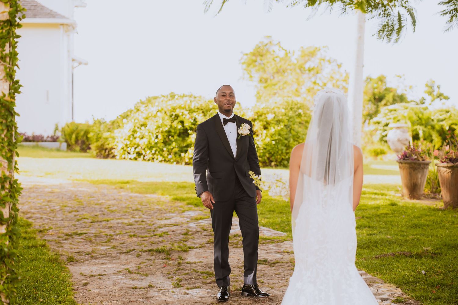 Bride and groom share a touching first look moment in a sunny garden setting.