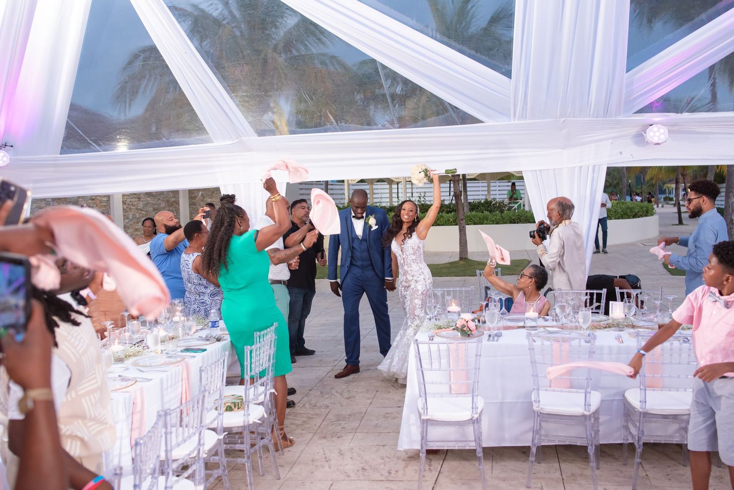 Guests celebrating at an outdoor tented wedding reception.