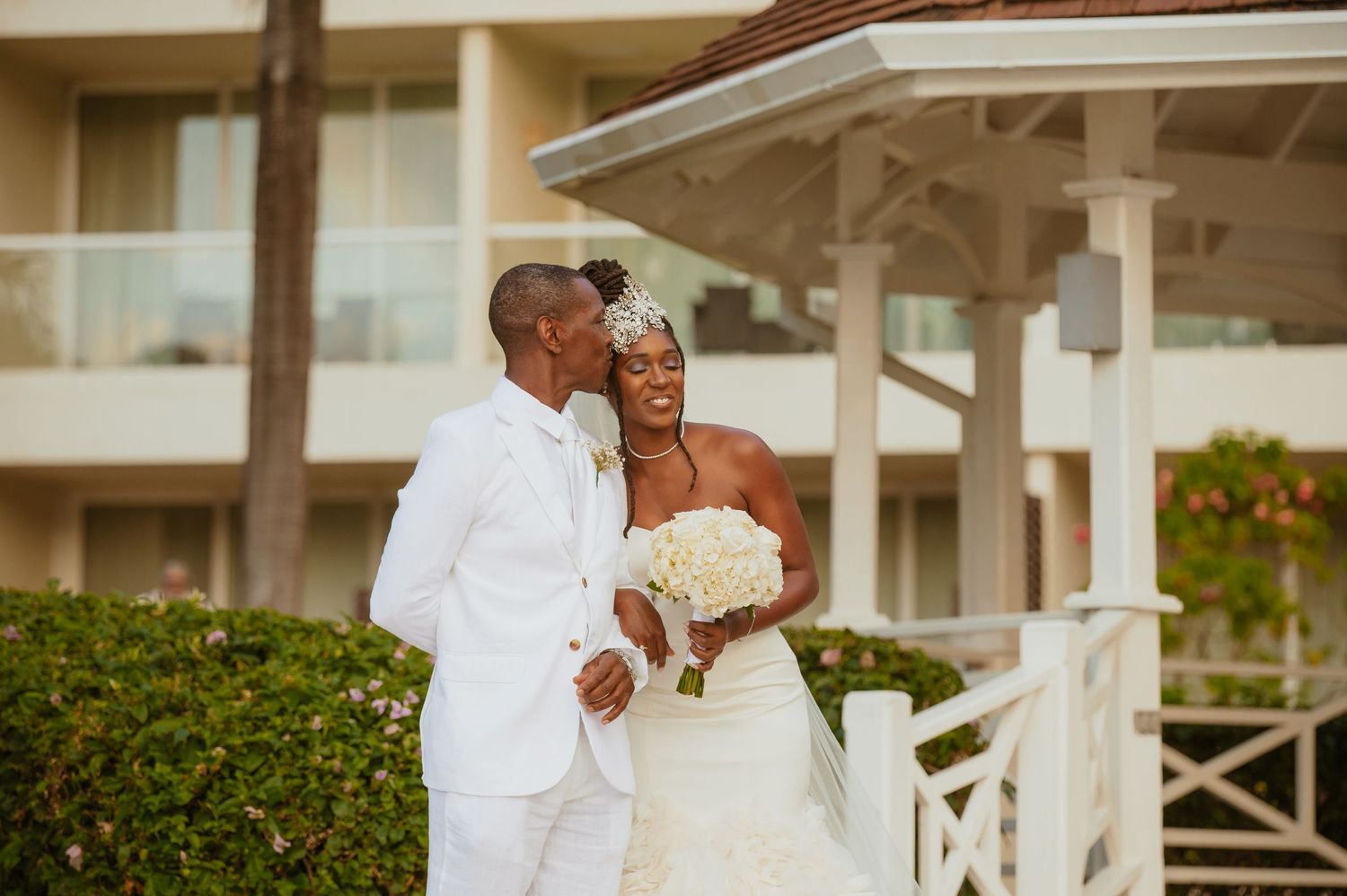 Wedding celebration on elegant white columned porch with landscaped gardens.