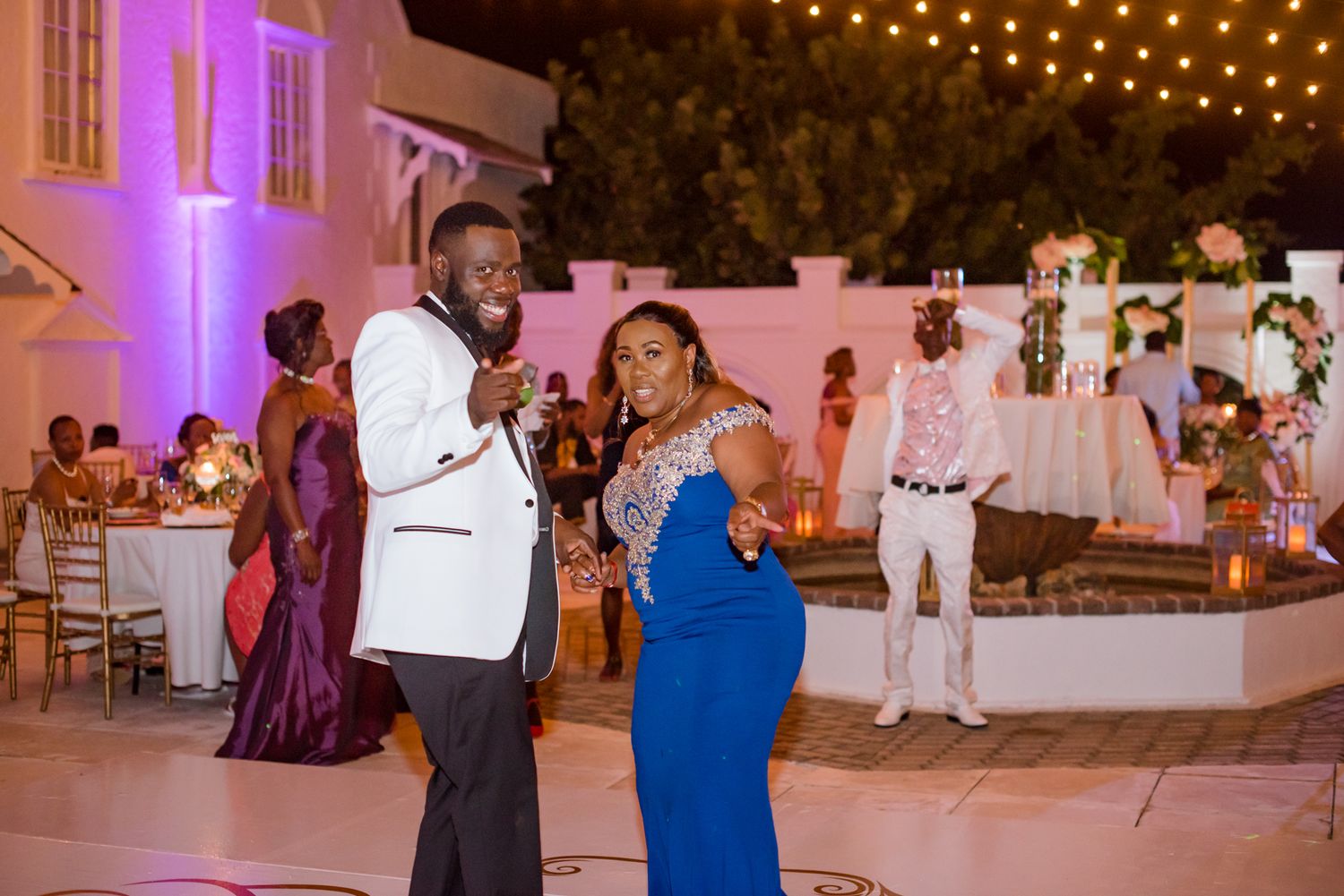 Couples dancing at an evening wedding reception under string lights.
