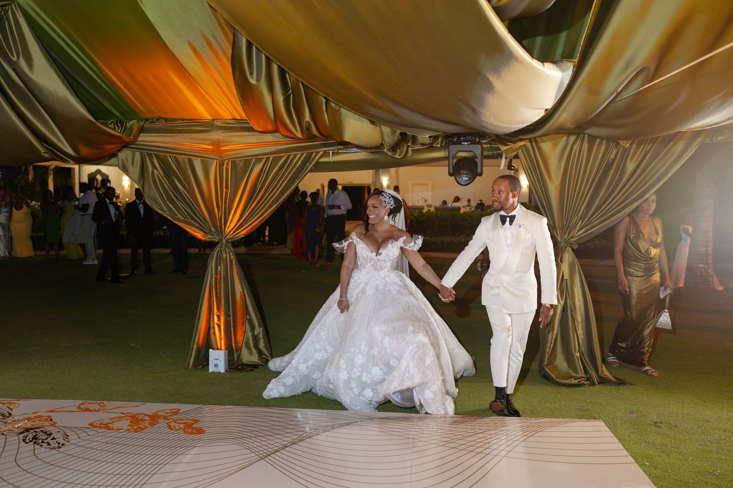 Elegant outdoor wedding reception under draped fabric tent with ambient lighting.