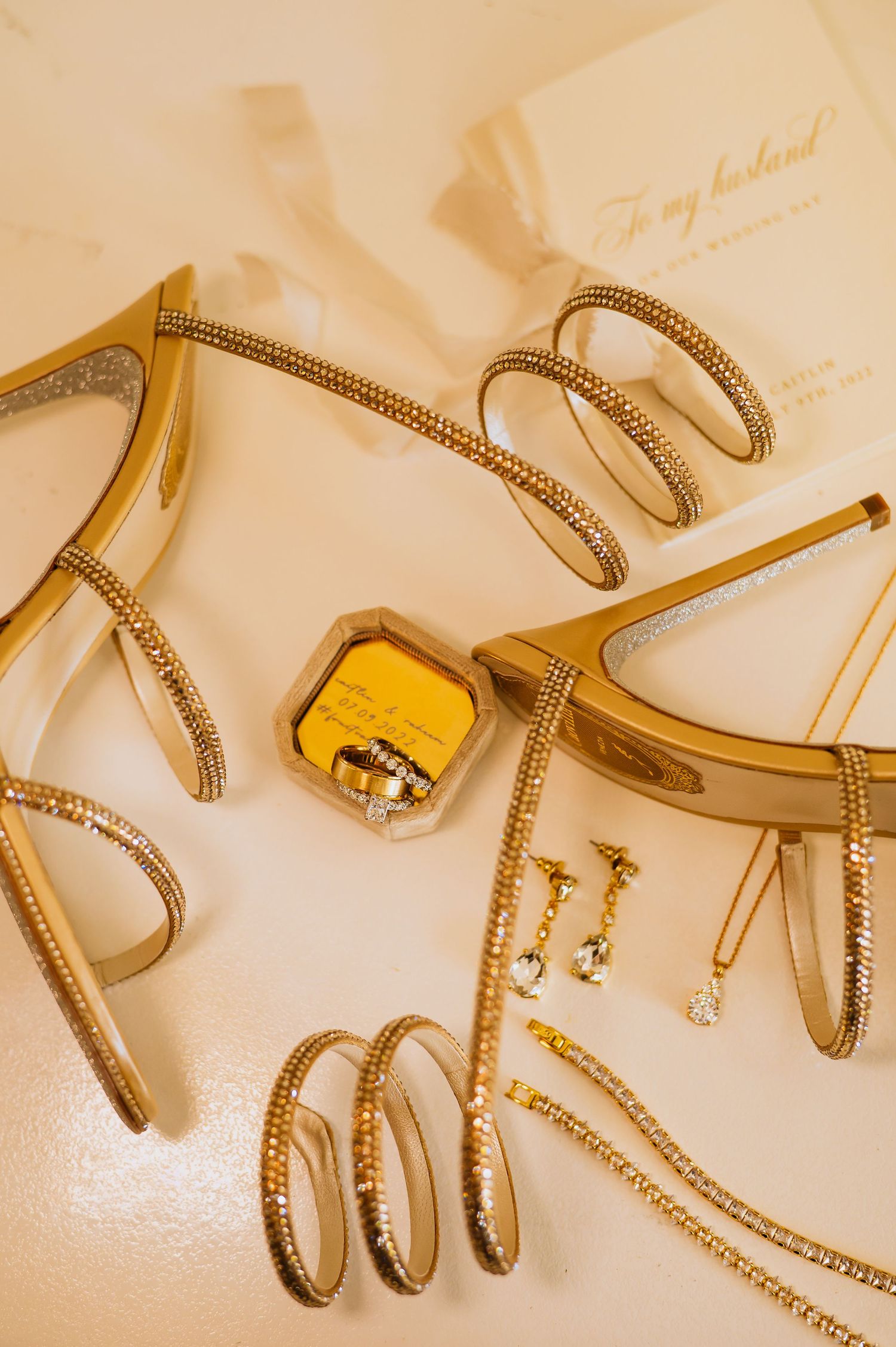 Gold and crystal wedding jewelry laid out on a white surface.
