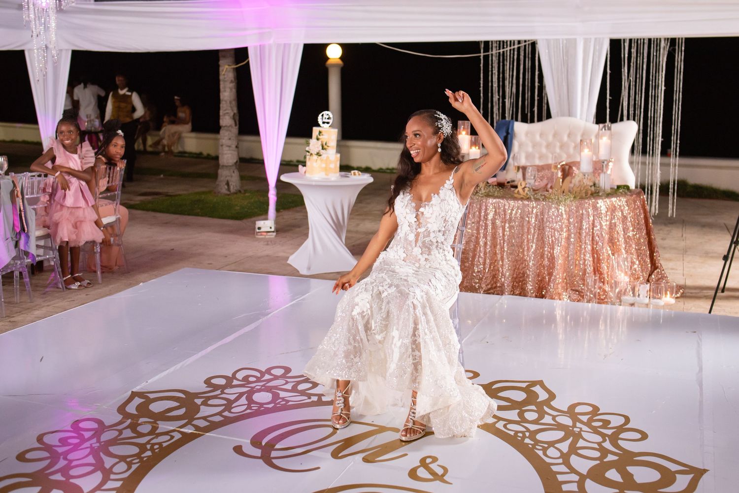 An elegant wedding reception space features white draping and ornate floor designs.