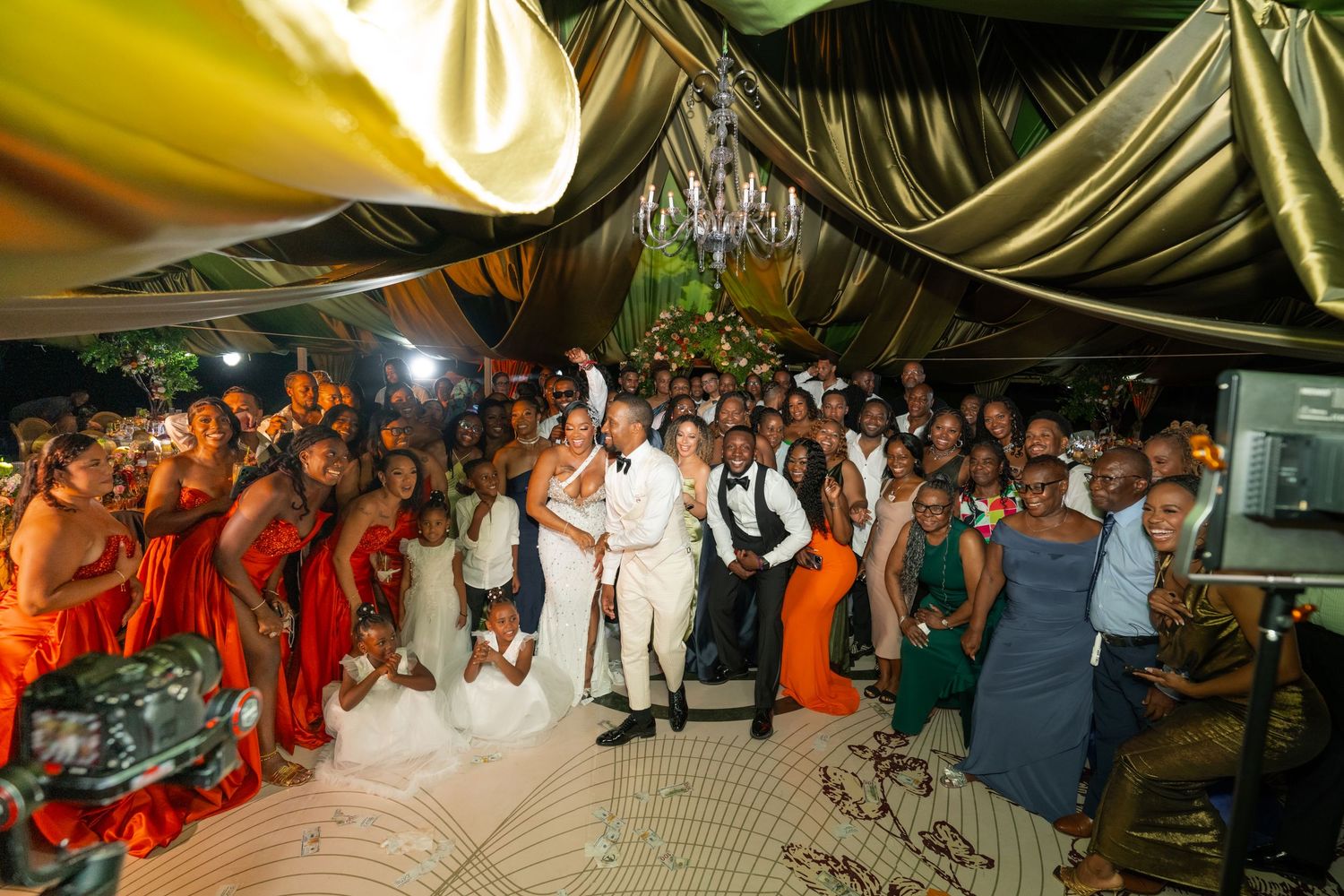 Wedding reception party scene with guests dancing under draped fabric ceiling decorations.
