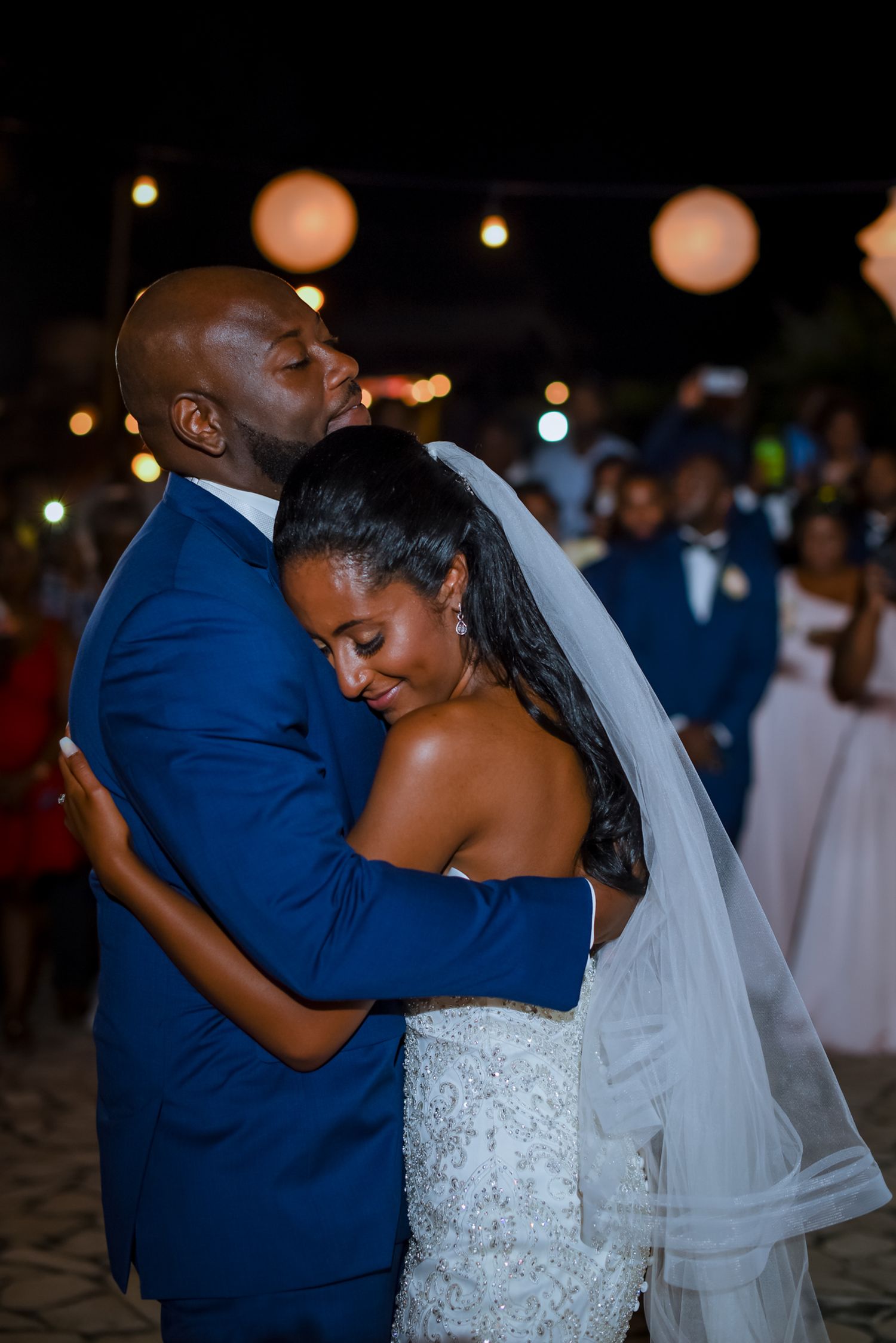 Romantic dance moment at an evening wedding reception with string lights overhead.