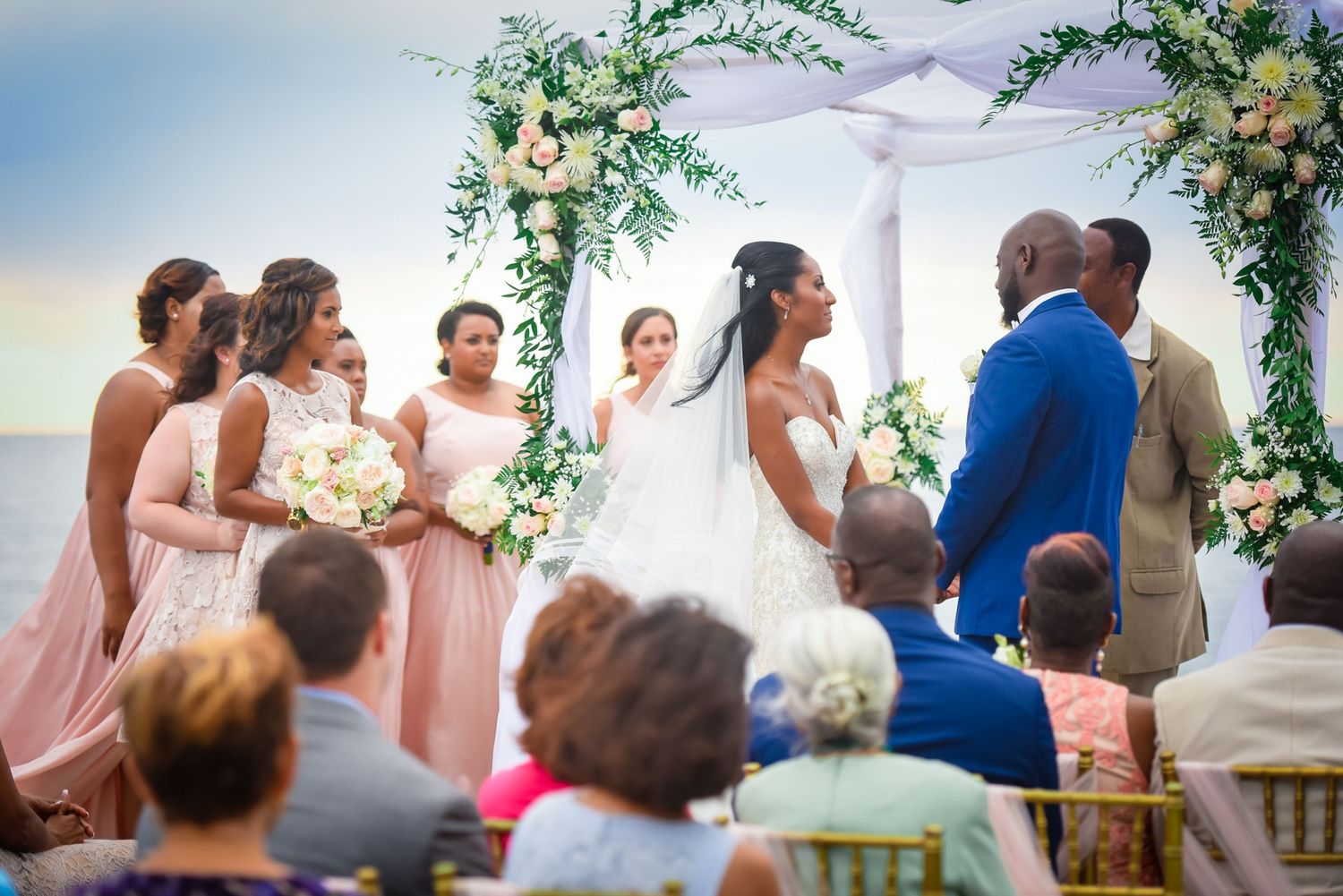 Outdoor wedding ceremony setup with white chairs and floral decorations.