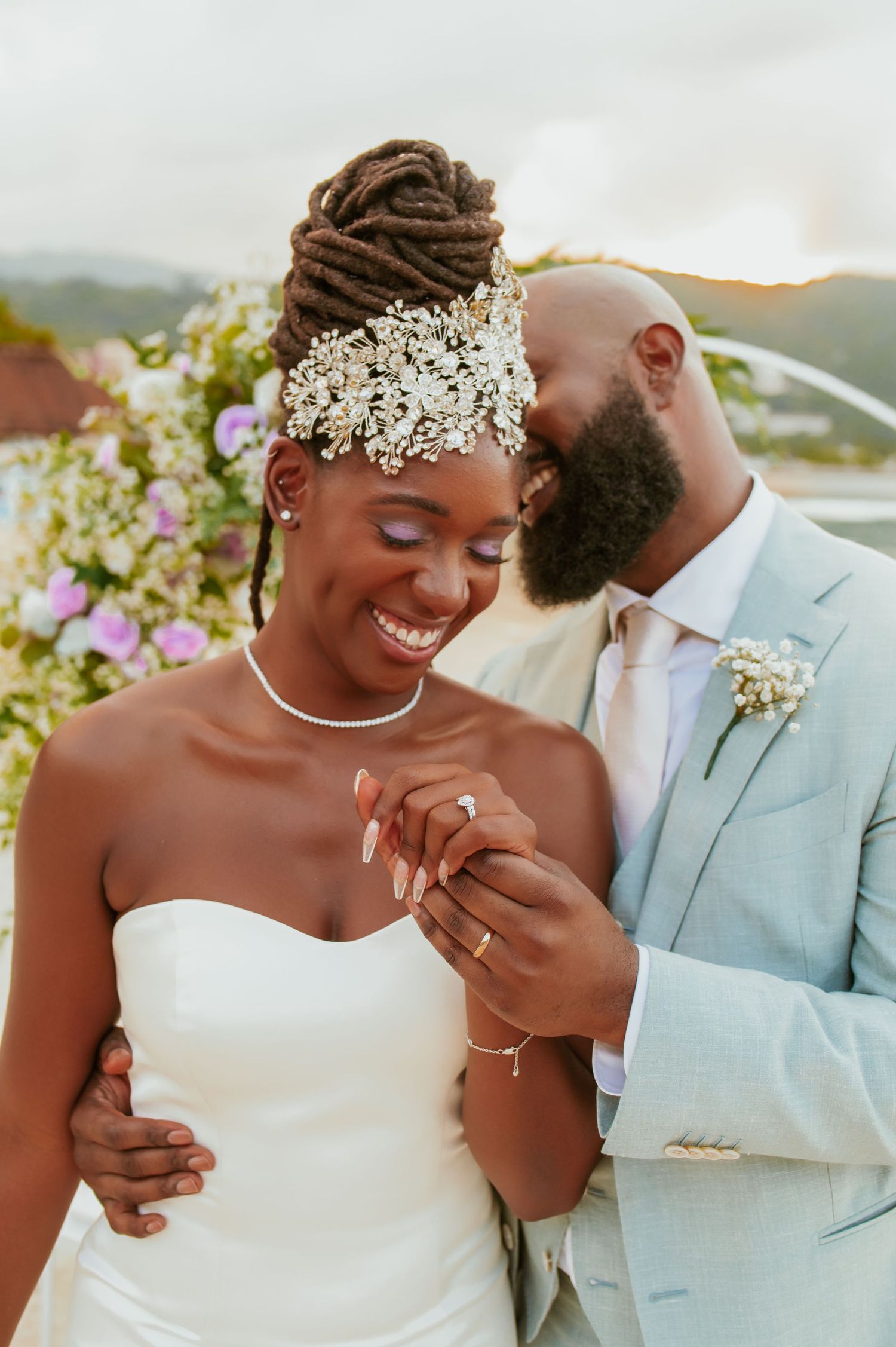 Joyful wedding couple shares romantic moment under floral arch on beachfront.