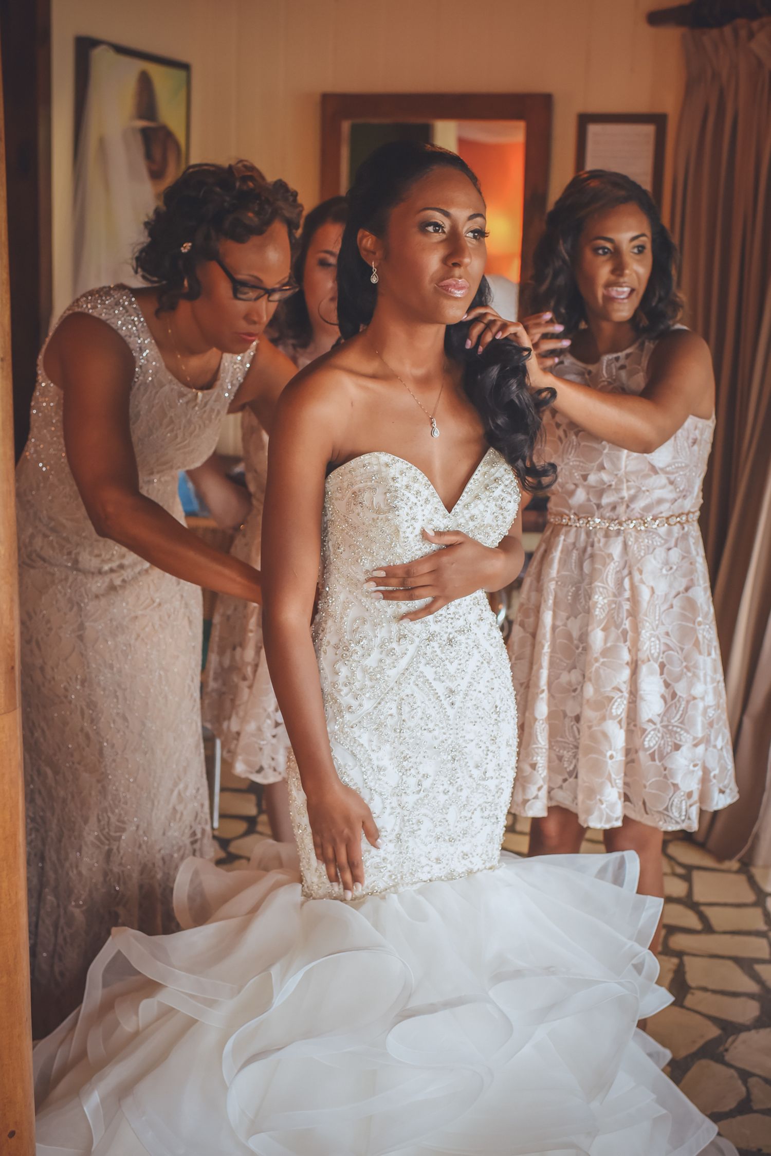 Wedding party in sparkly champagne dresses helping with bridal preparations.