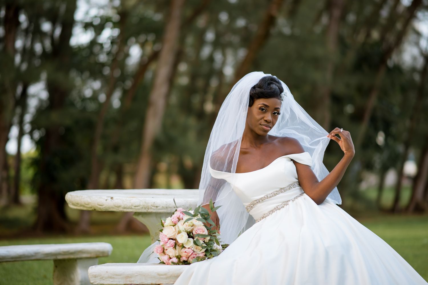 Bride in elegant white gown poses for dramatic portraits outdoors.