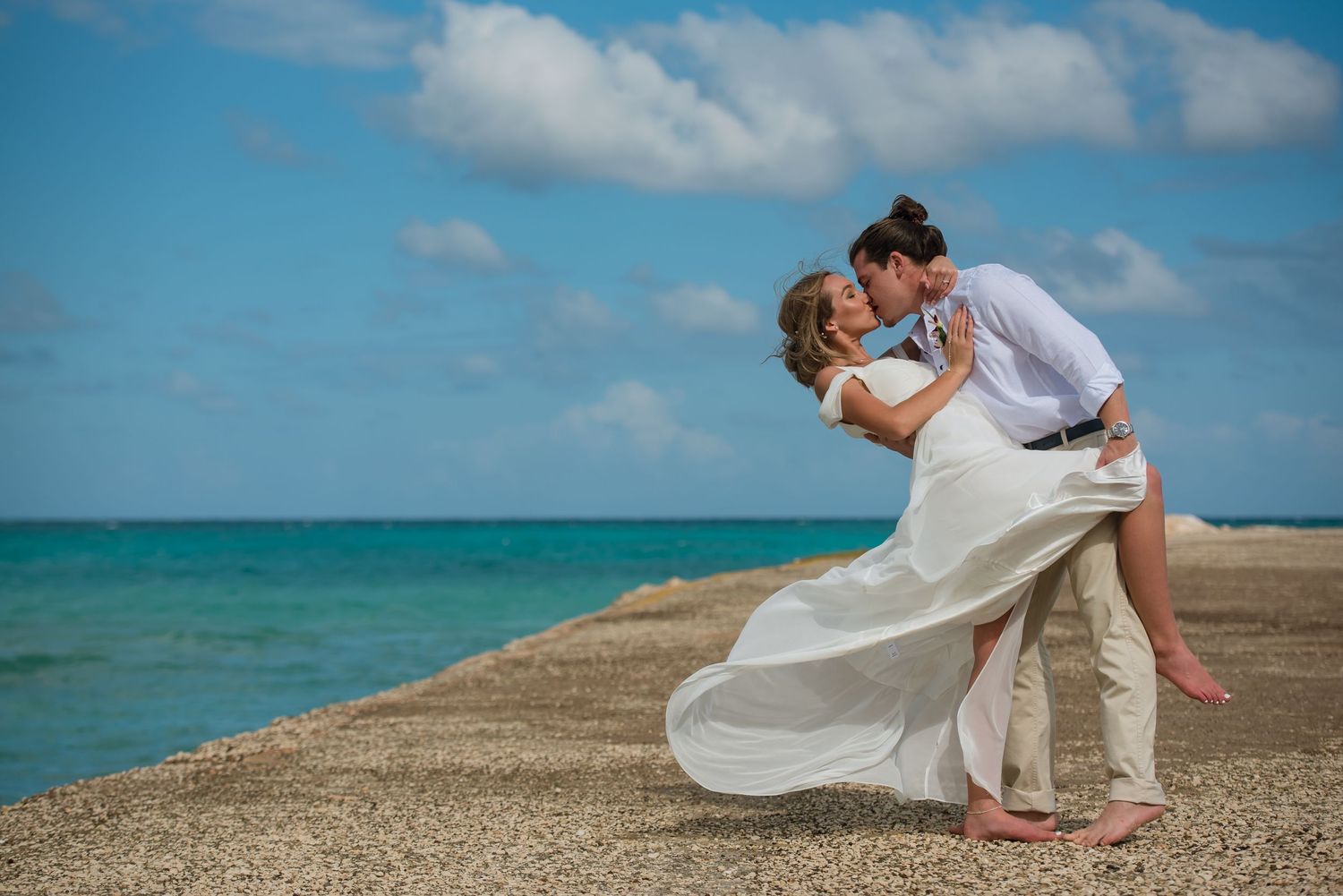 Destination wedding photography session with waves crashing against tropical shoreline.