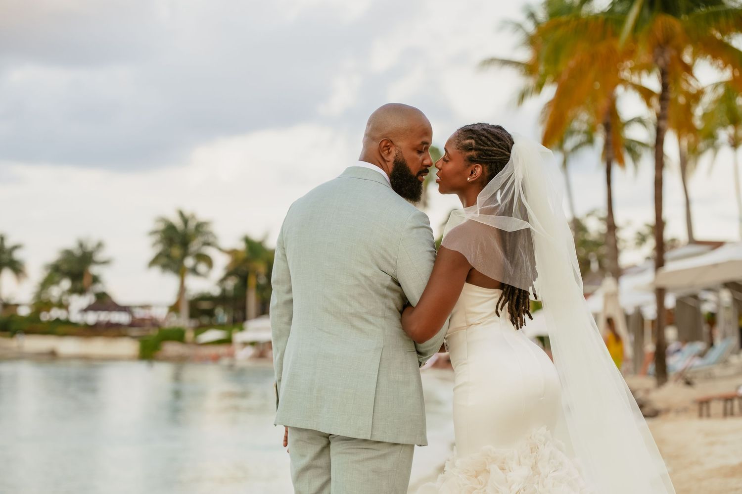 A beachside wedding photoshoot with palm trees and tropical resort scenery in the background.