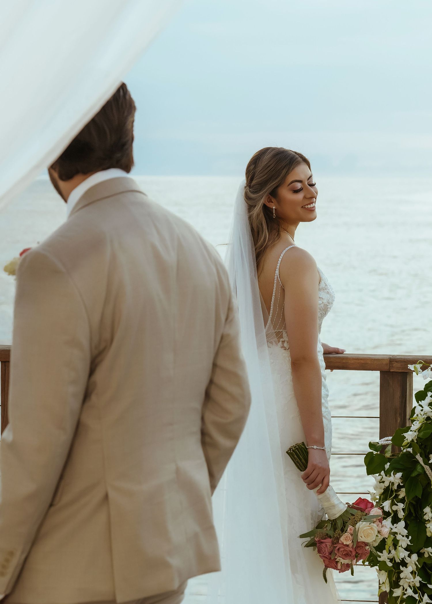 Bride and groom share an intimate moment on a beachfront balcony during their destination wedding ceremony.