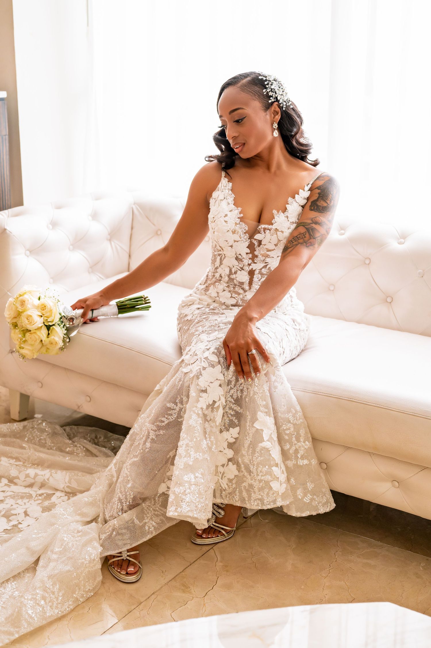 Wedding dress detail shots showing intricate lace pattern and flowing skirt on white couch.