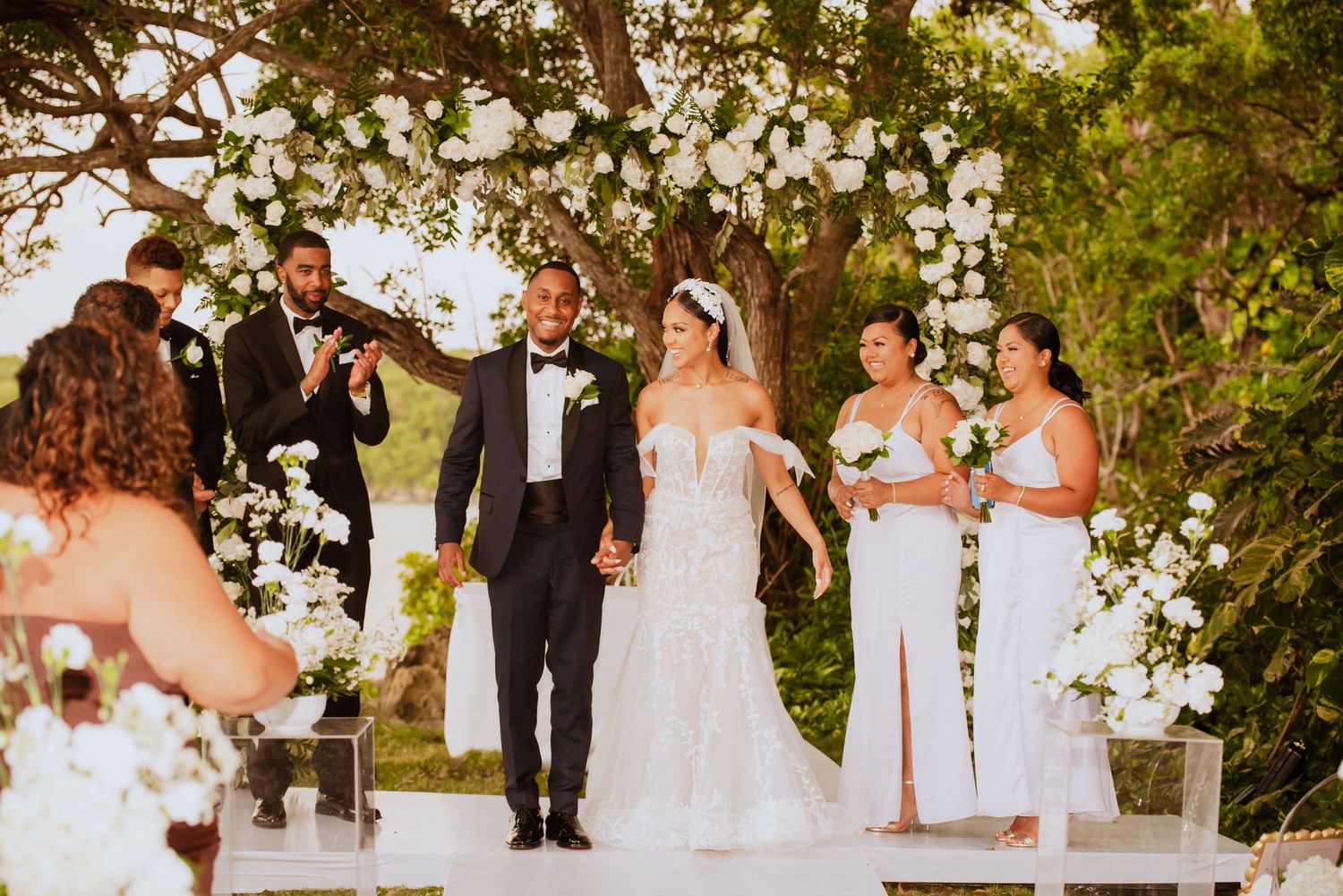 Elegant outdoor wedding ceremony setup with white floral arrangements and natural greenery.