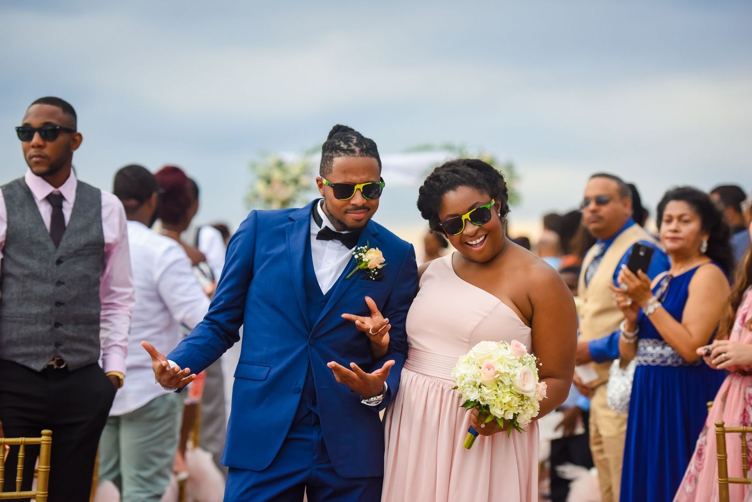 Wedding party members enjoying festivities at a seaside ceremony.