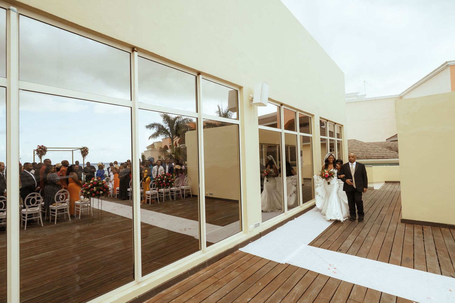 A panoramic view of an empty white deck with glass railings and chairs set up for an event.