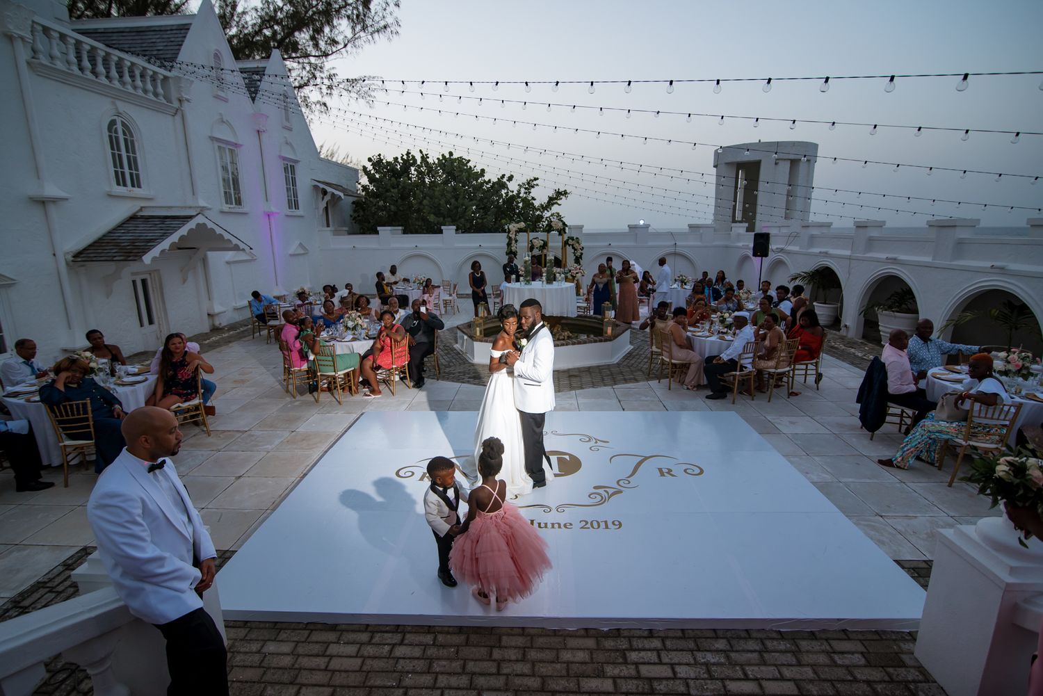 Evening outdoor wedding reception with string lights and scenic coastal views.