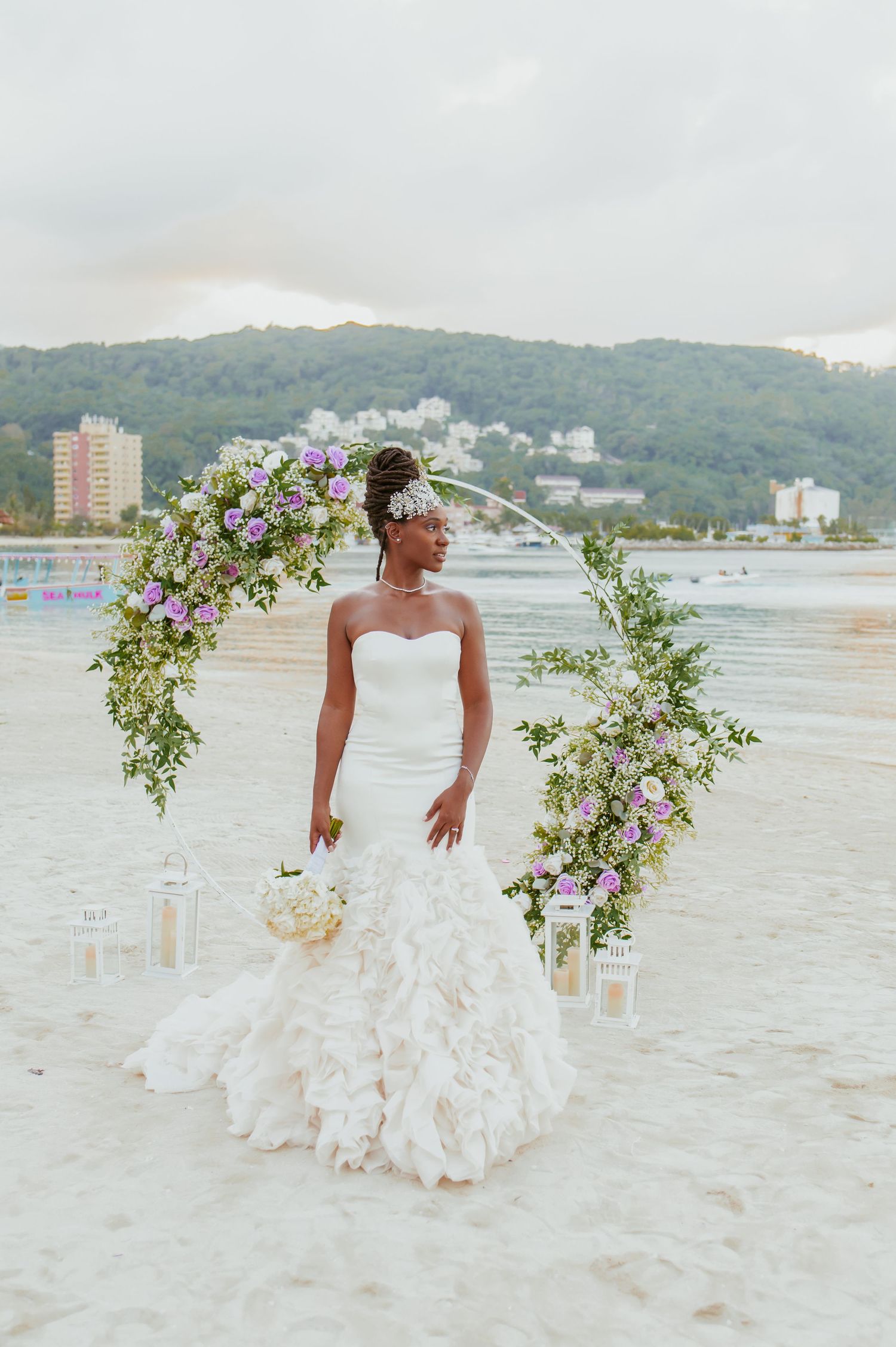 Beautiful beach wedding dress flows in the breeze against coastal landscape.
