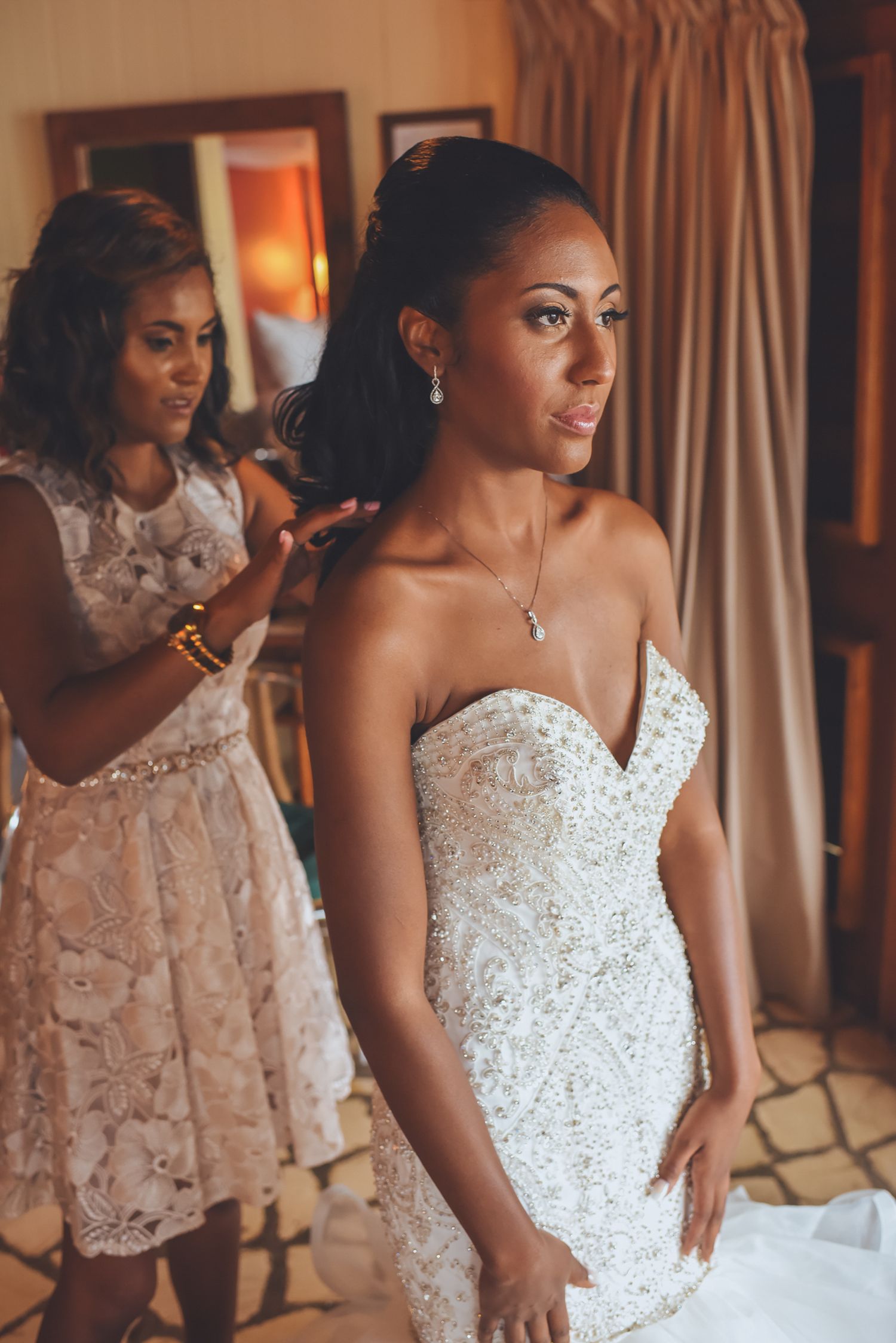 Bridesmaids in champagne lace dresses helping bride prepare for wedding day.