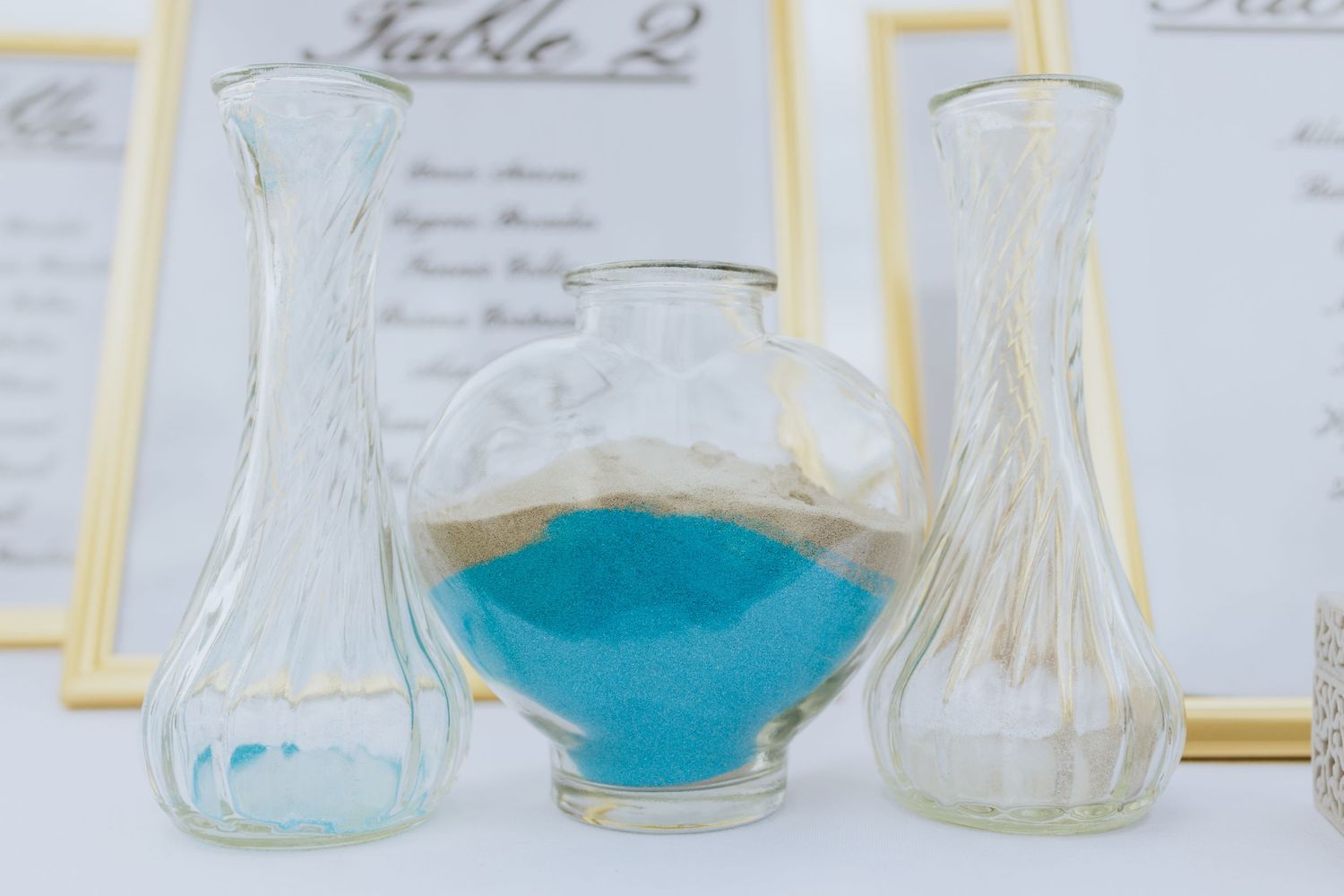Glass vases and table numbers with gold accents for wedding reception decor.
