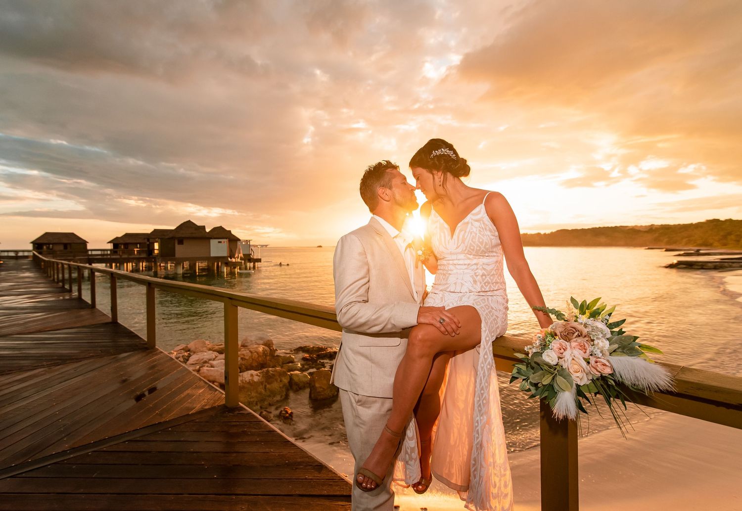 Romantic sunset beach photoshoot with couple silhouetted against orange sky.