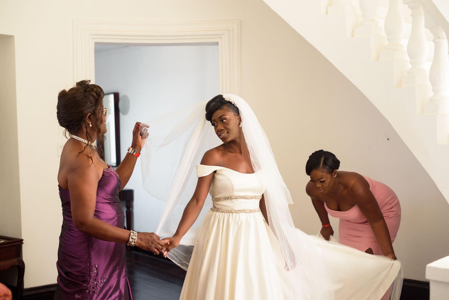 Wedding dress fitting session with multiple people helping with adjustments.