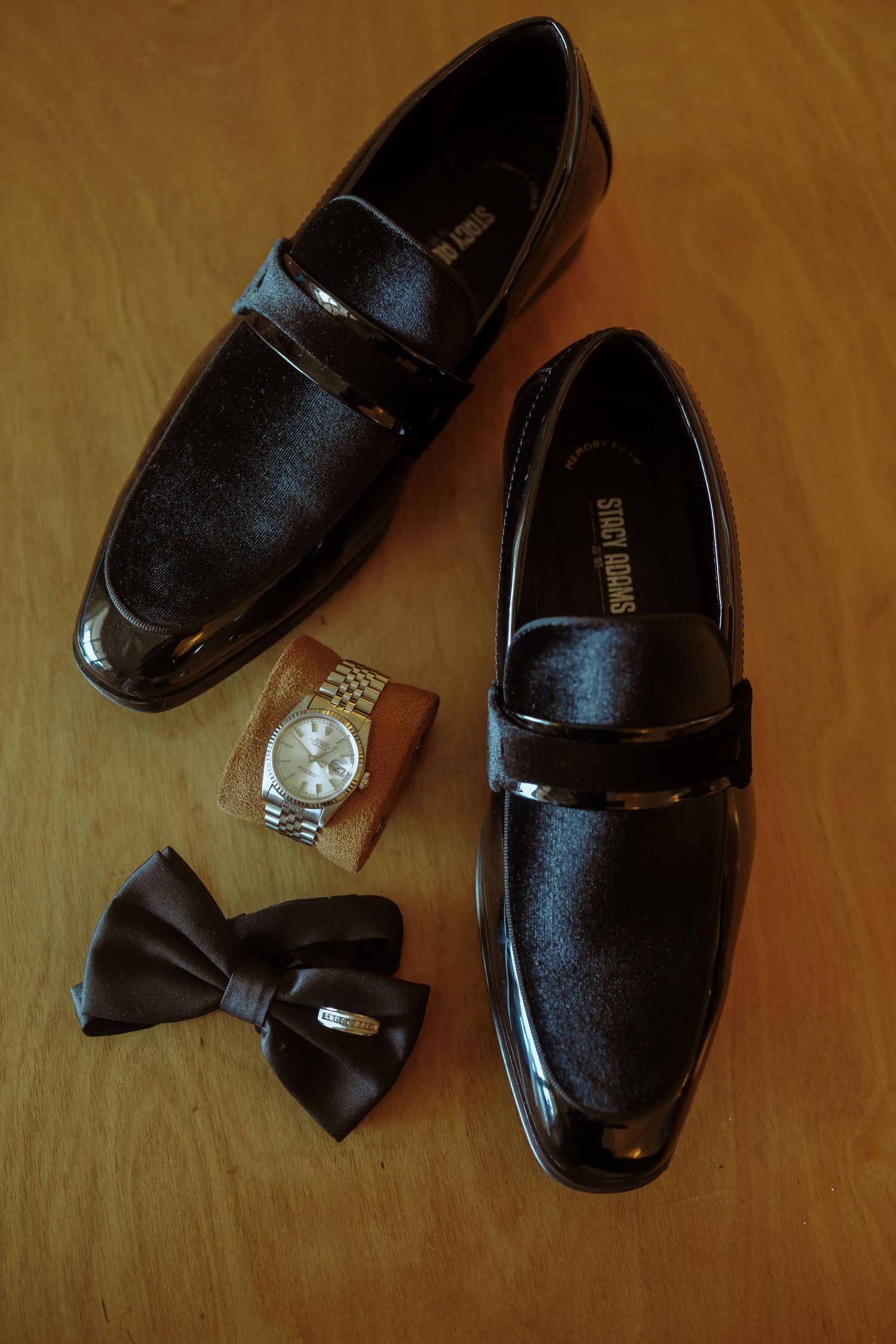 Black formal dress shoes with bow ties arranged on a wooden surface.