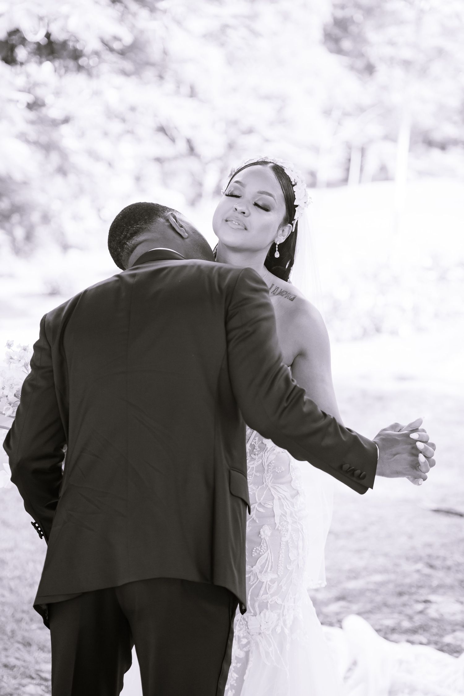Black and white photo of wedding couple's first look reaction in outdoor setting.