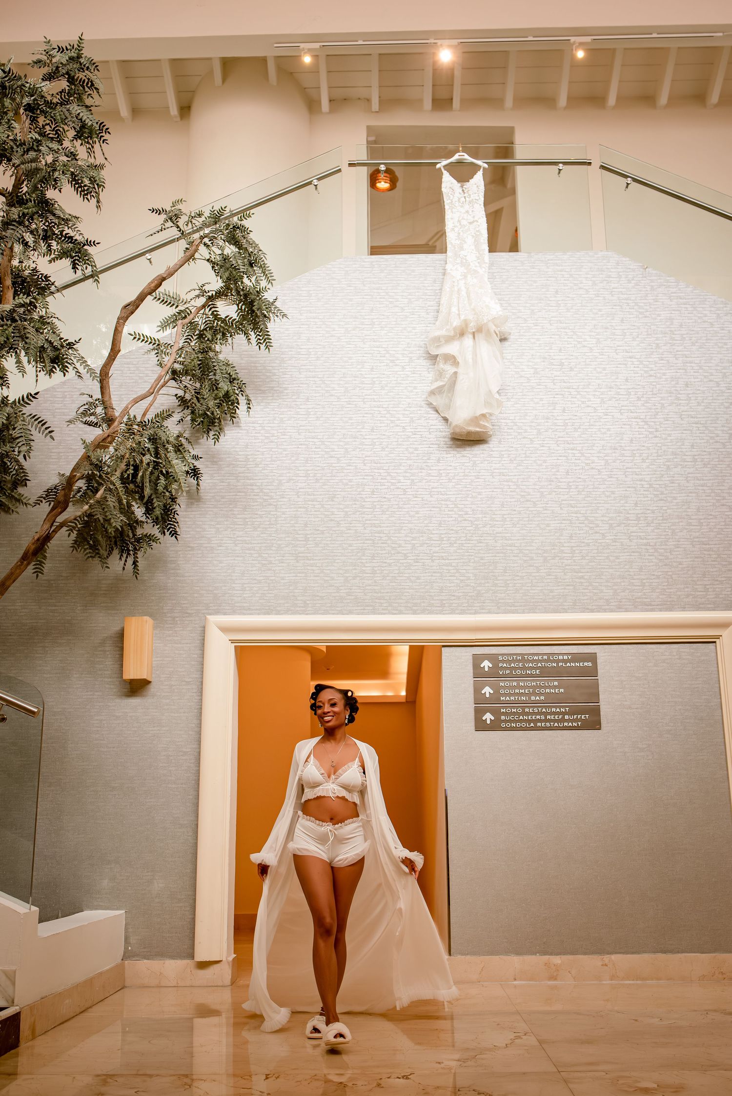 Elegant white room with orange doorway and hanging dress display.