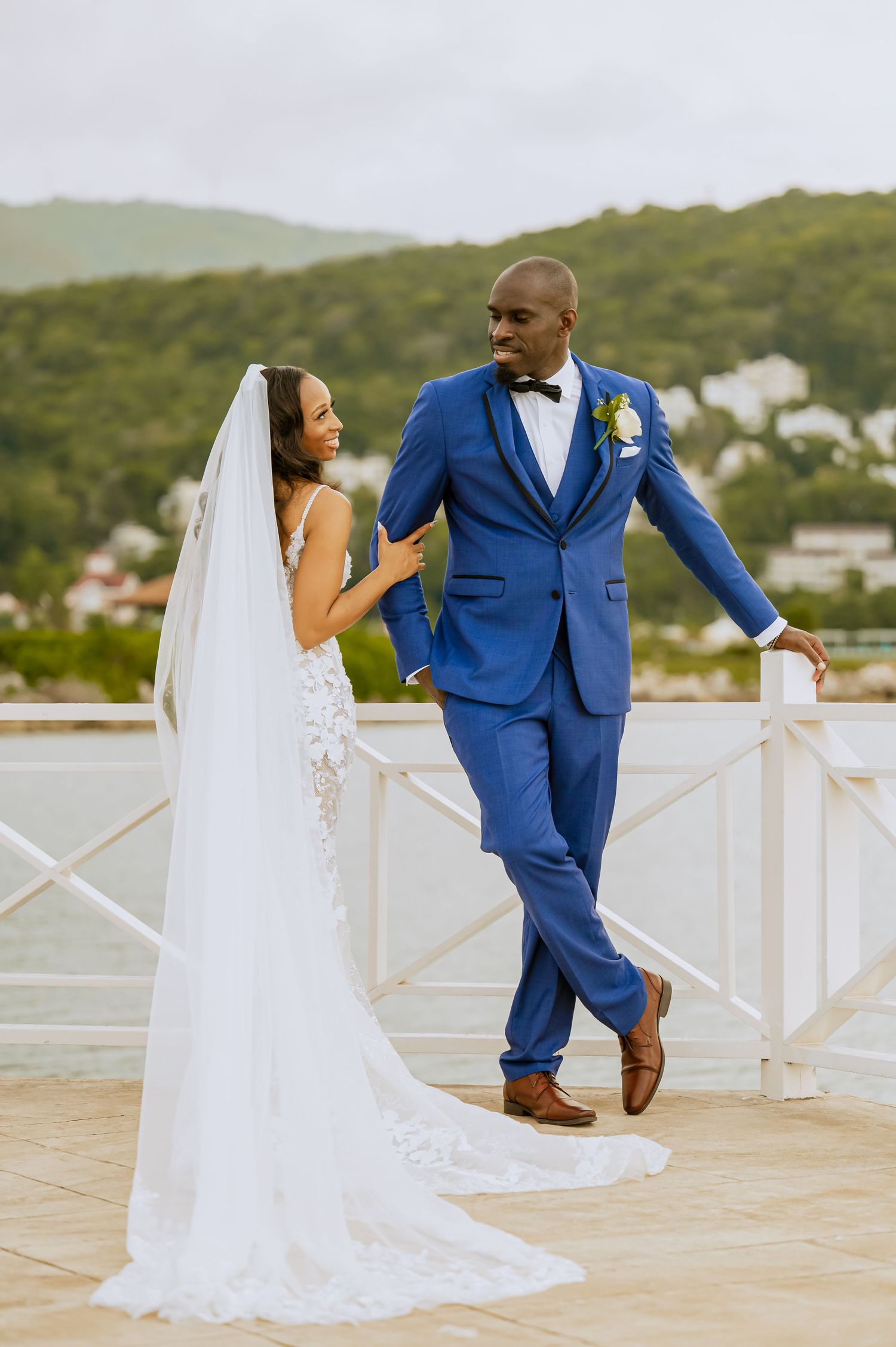 Wedding couple walks together on terrace with mountain view in background.