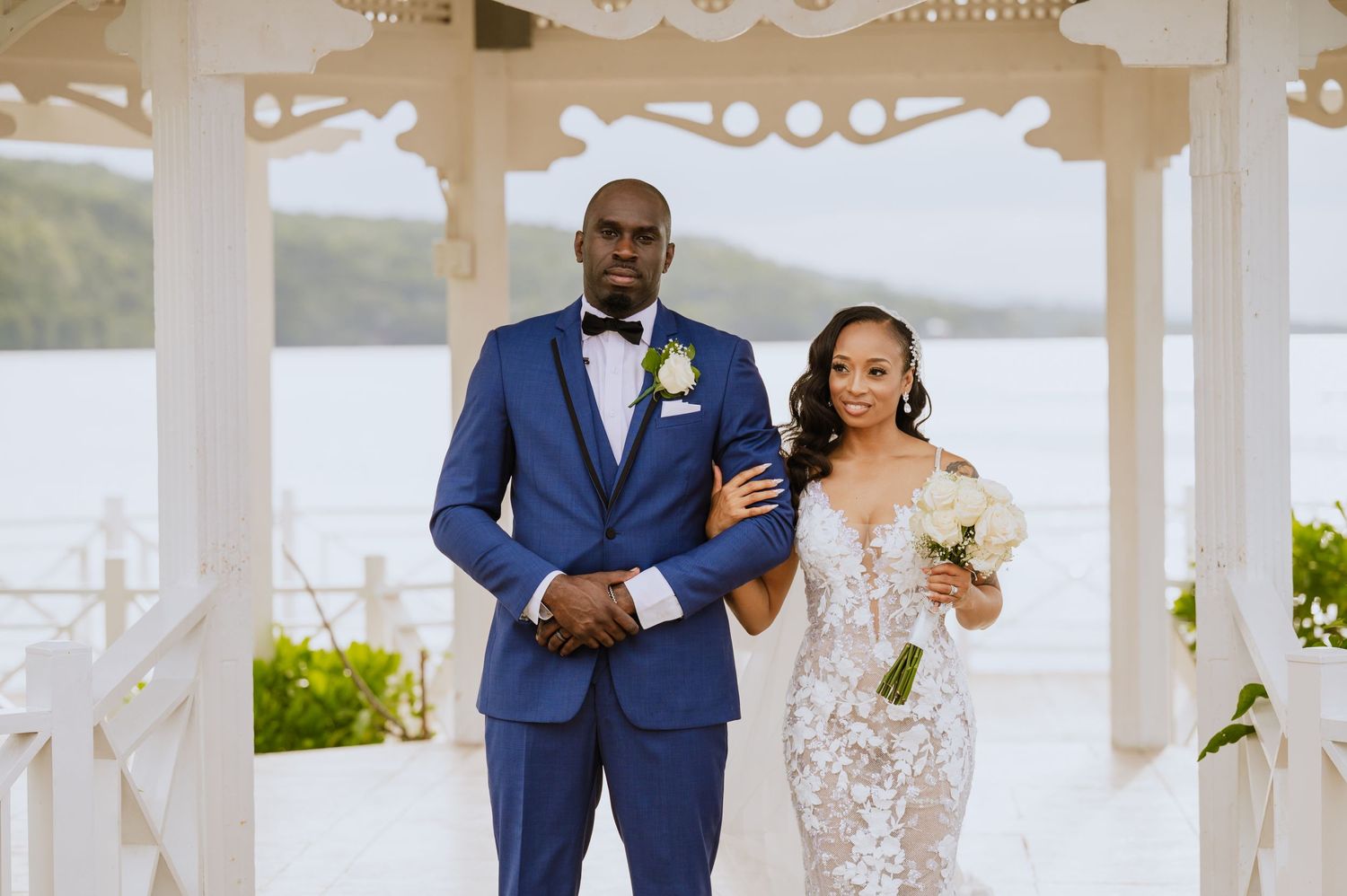 Newlyweds pose together in a waterfront gazebo after their wedding ceremony.