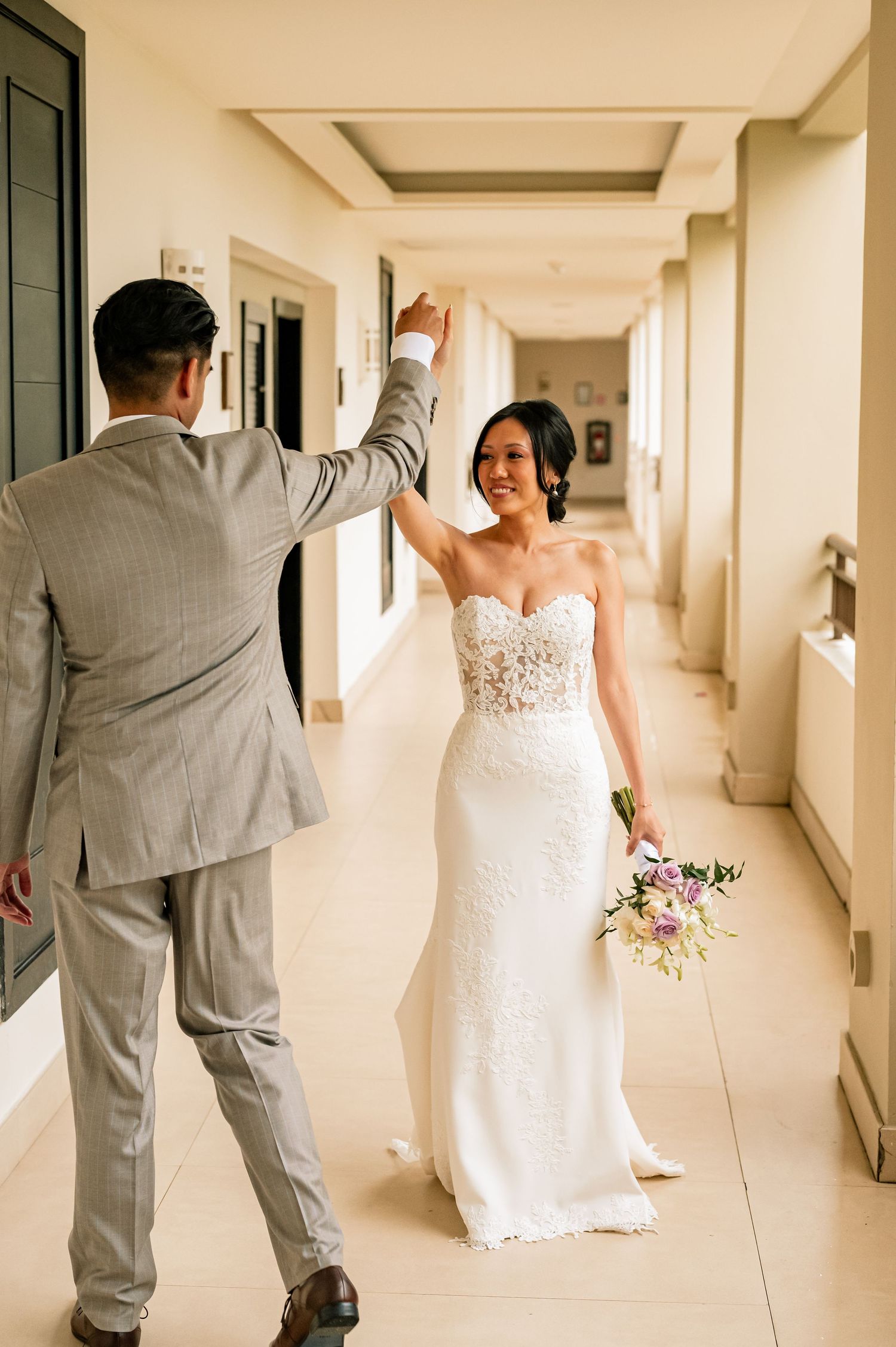 Candid wedding first look moments captured in a sunlit corridor.