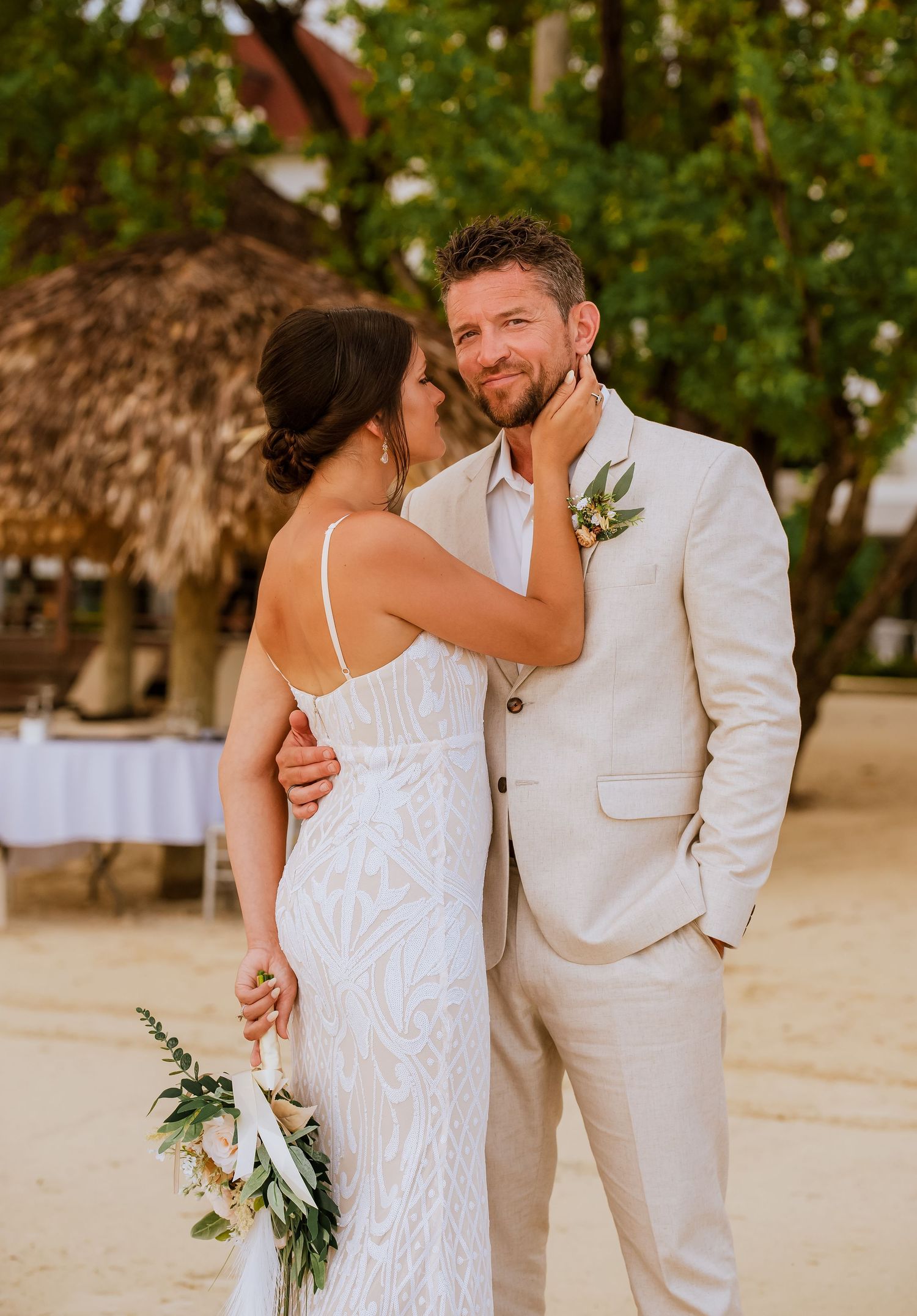 A couple shares tender moments on a sandy beach during their destination wedding.