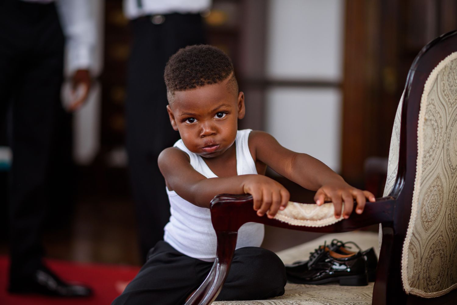 A young child sitting in formal attire during wedding preparations.