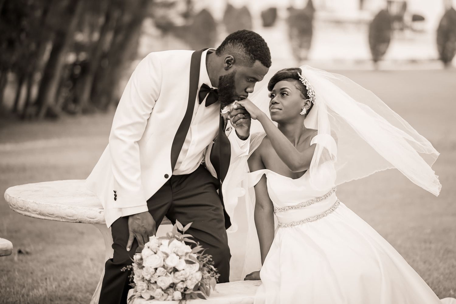 Wedding couple embraces in elegant black and white portraits against outdoor backdrop.