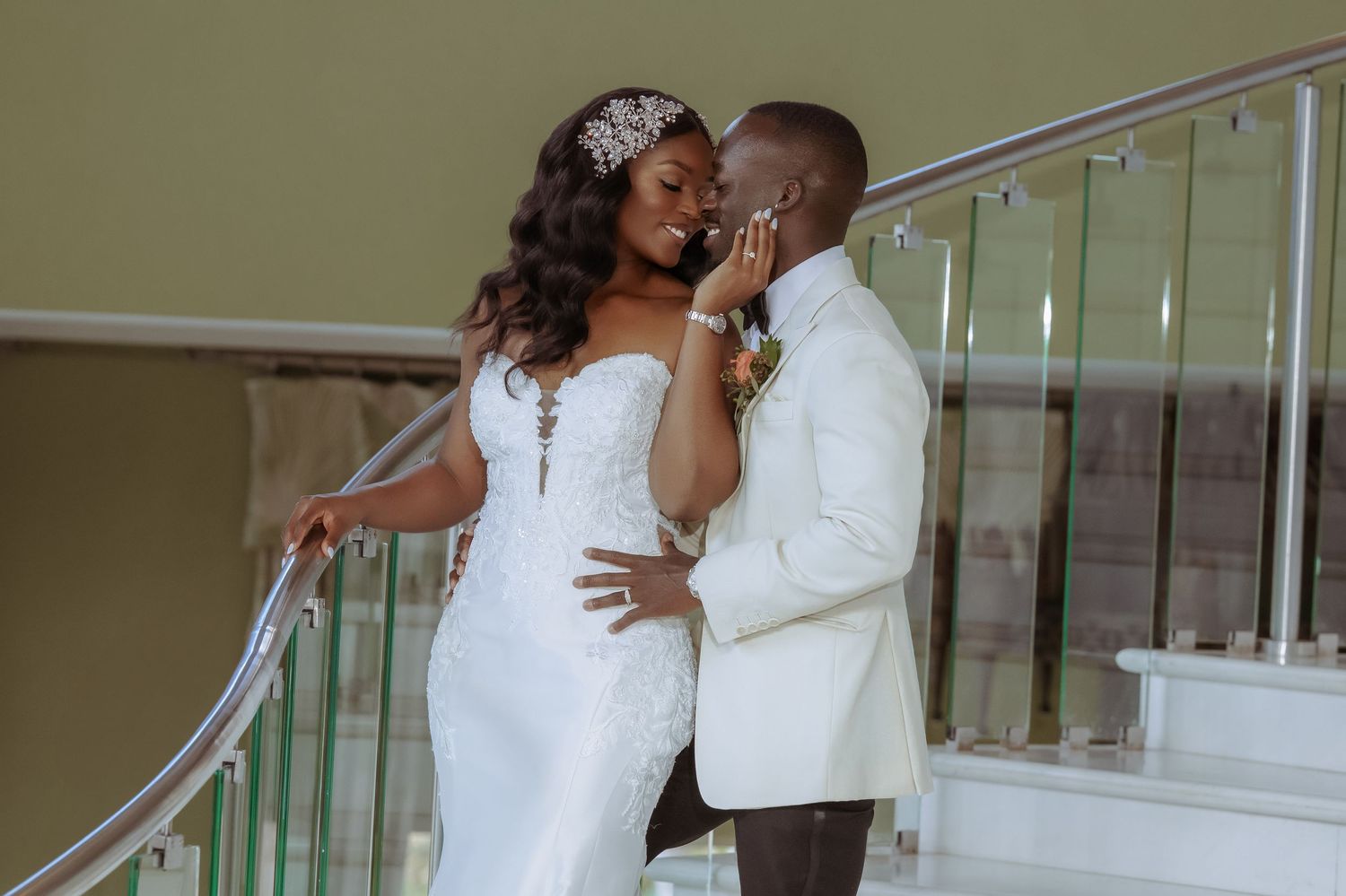 A tender embrace between a couple in white wedding attire on a modern staircase. Iberostar Montego Bay wedding