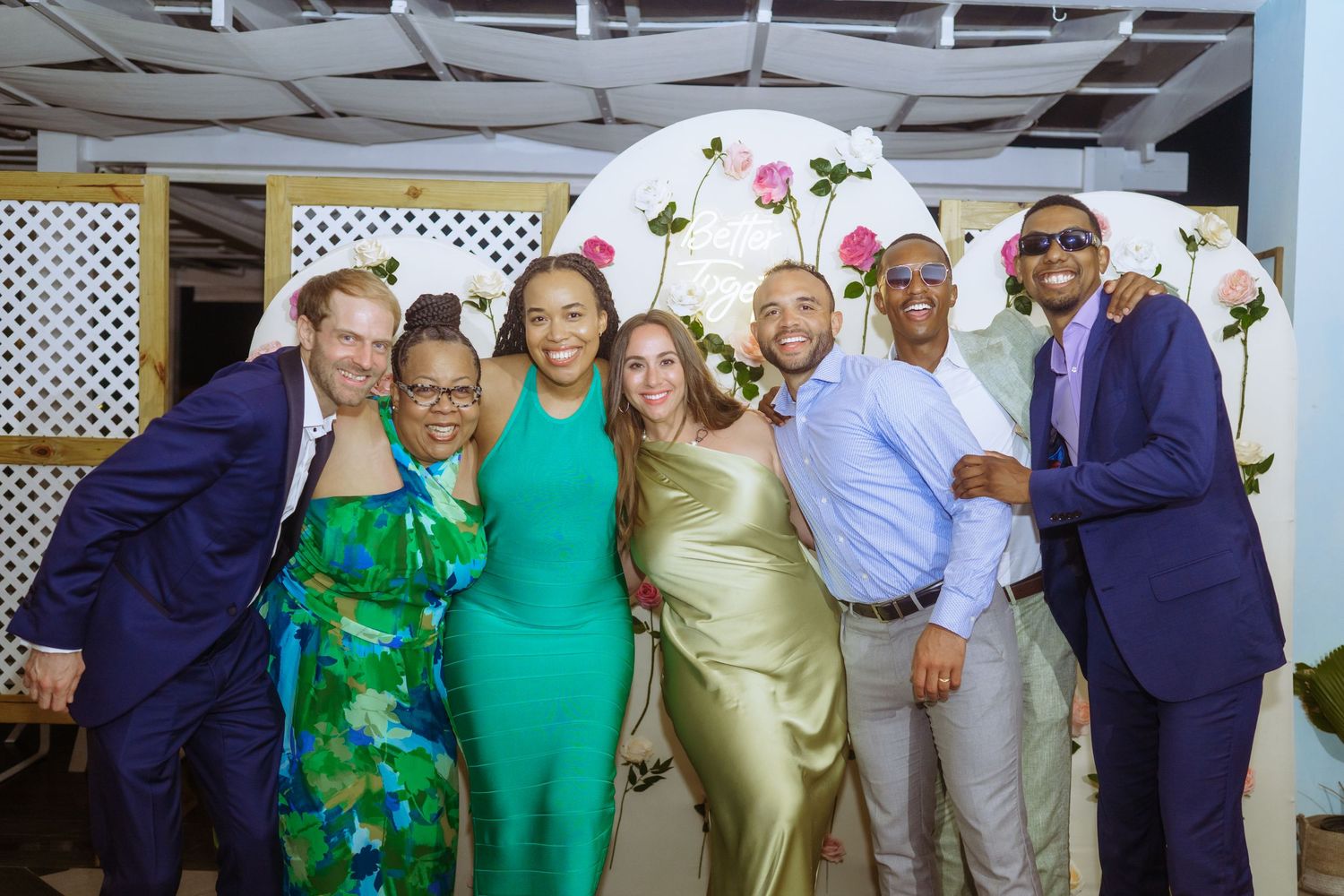 Wedding party group photo with members wearing coordinated green, navy and neutral tones.